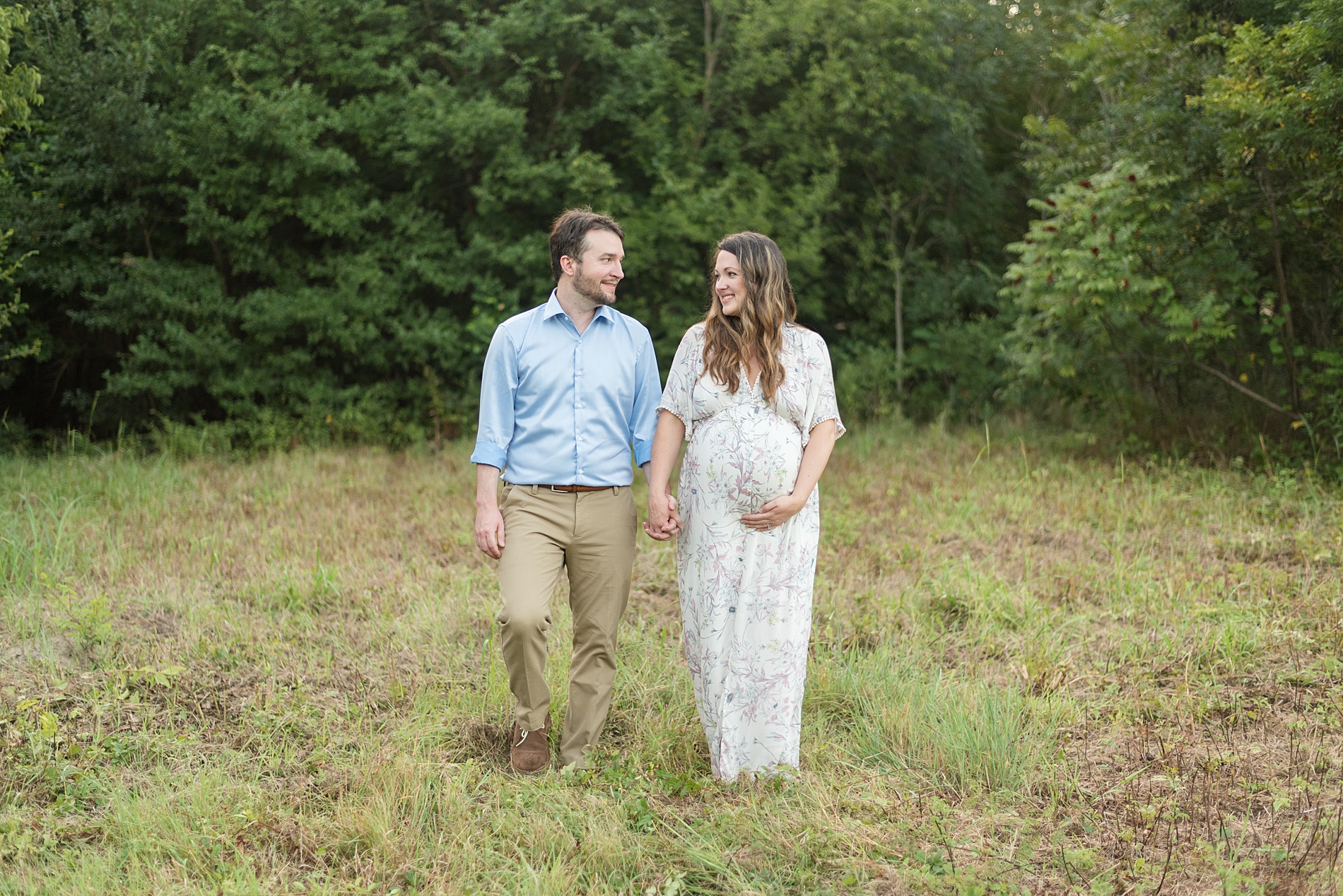 couple walks together holding hands at Arbor Hills during maternity session 