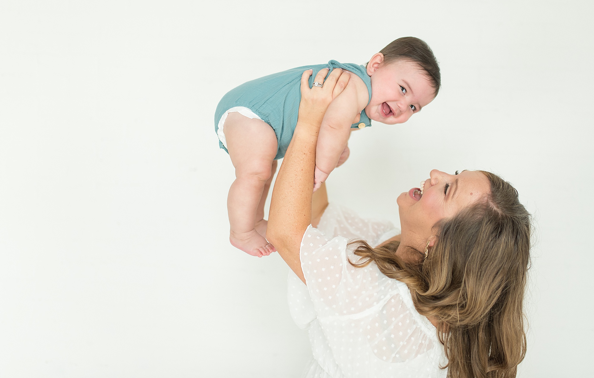 mom holds baby boy up in the air by TX newborn photography Lindsey Dutton
