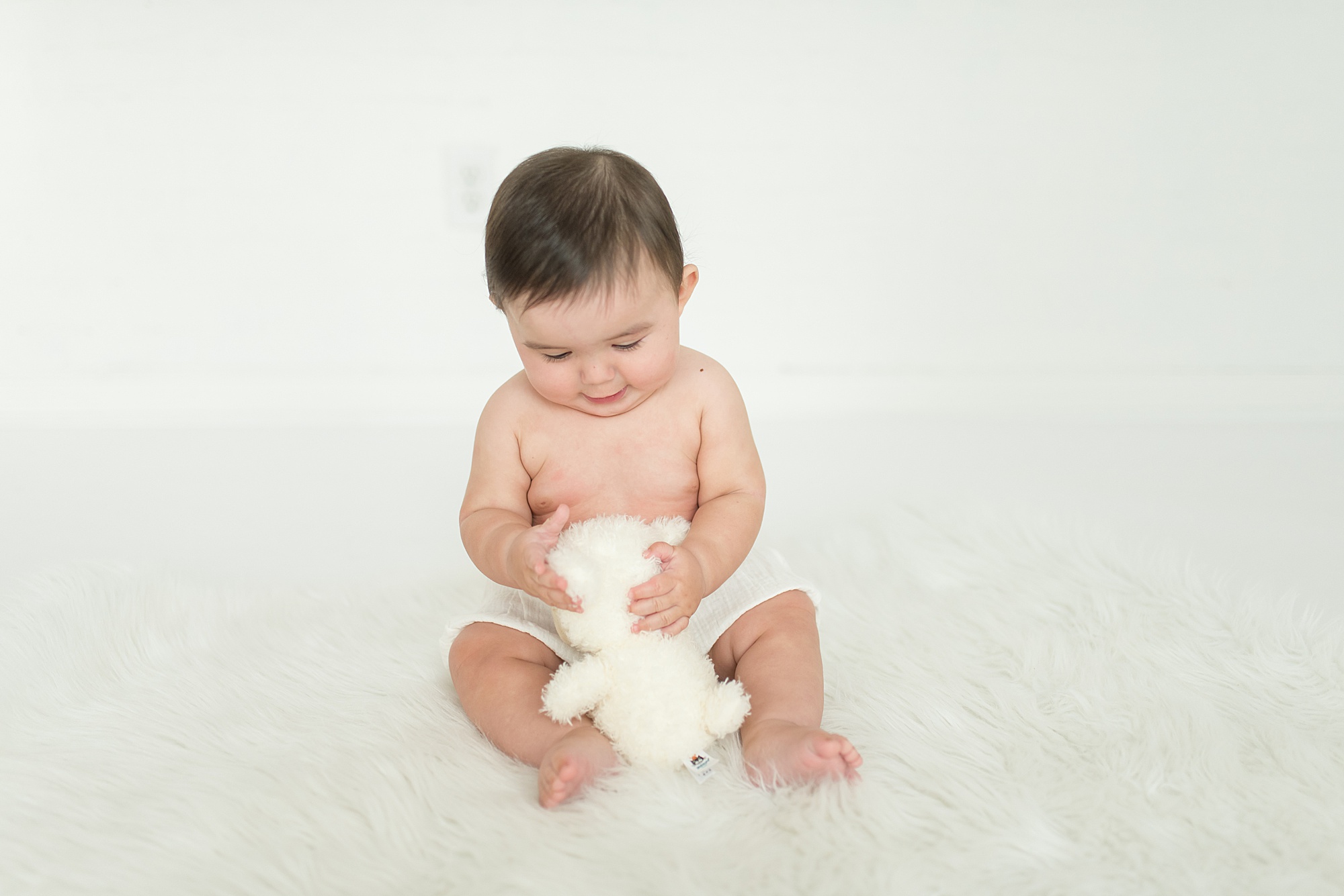 Little elm 6-month old plays with white stuffed animal