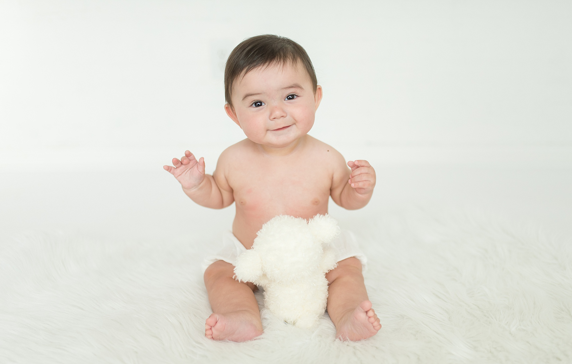 Little elm 6-month old smiles and plays with white stuffed animal 