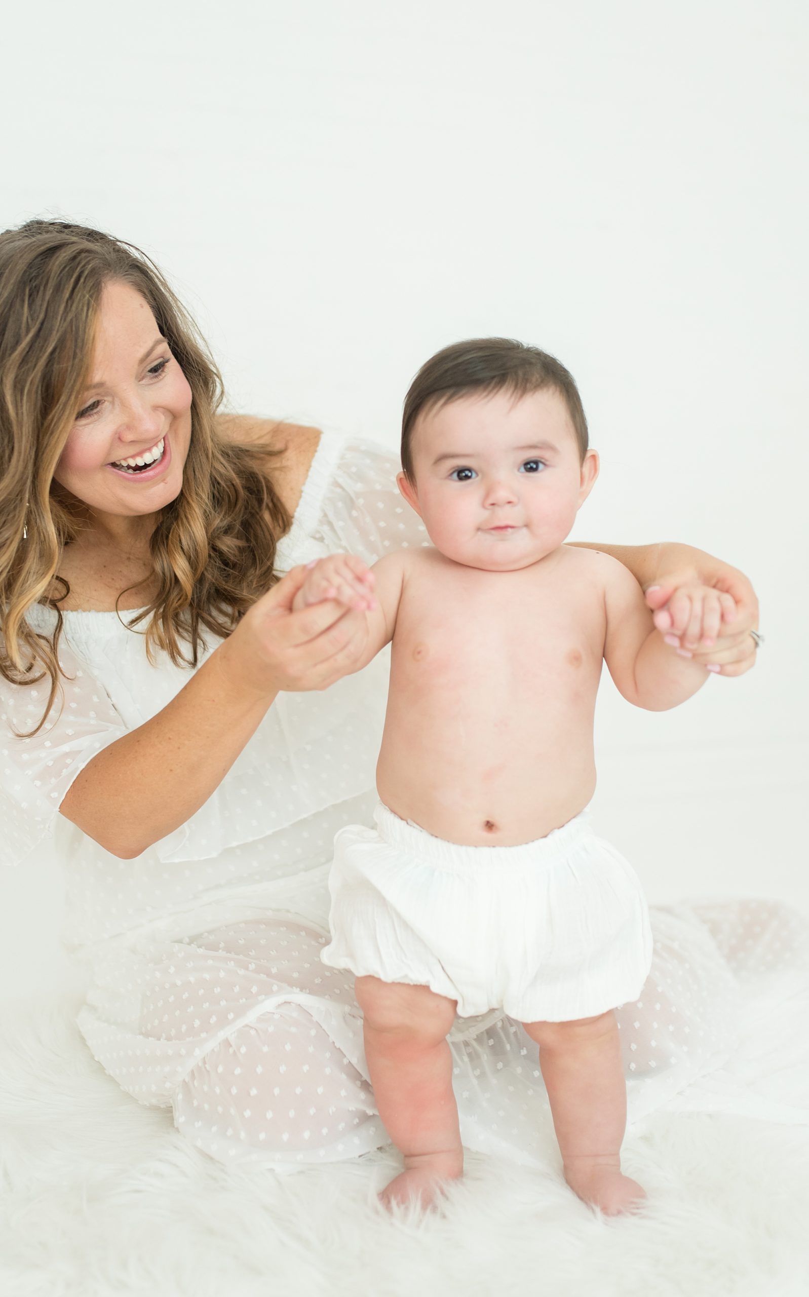 baby stands up with a little help from his mom during milestone portraits 