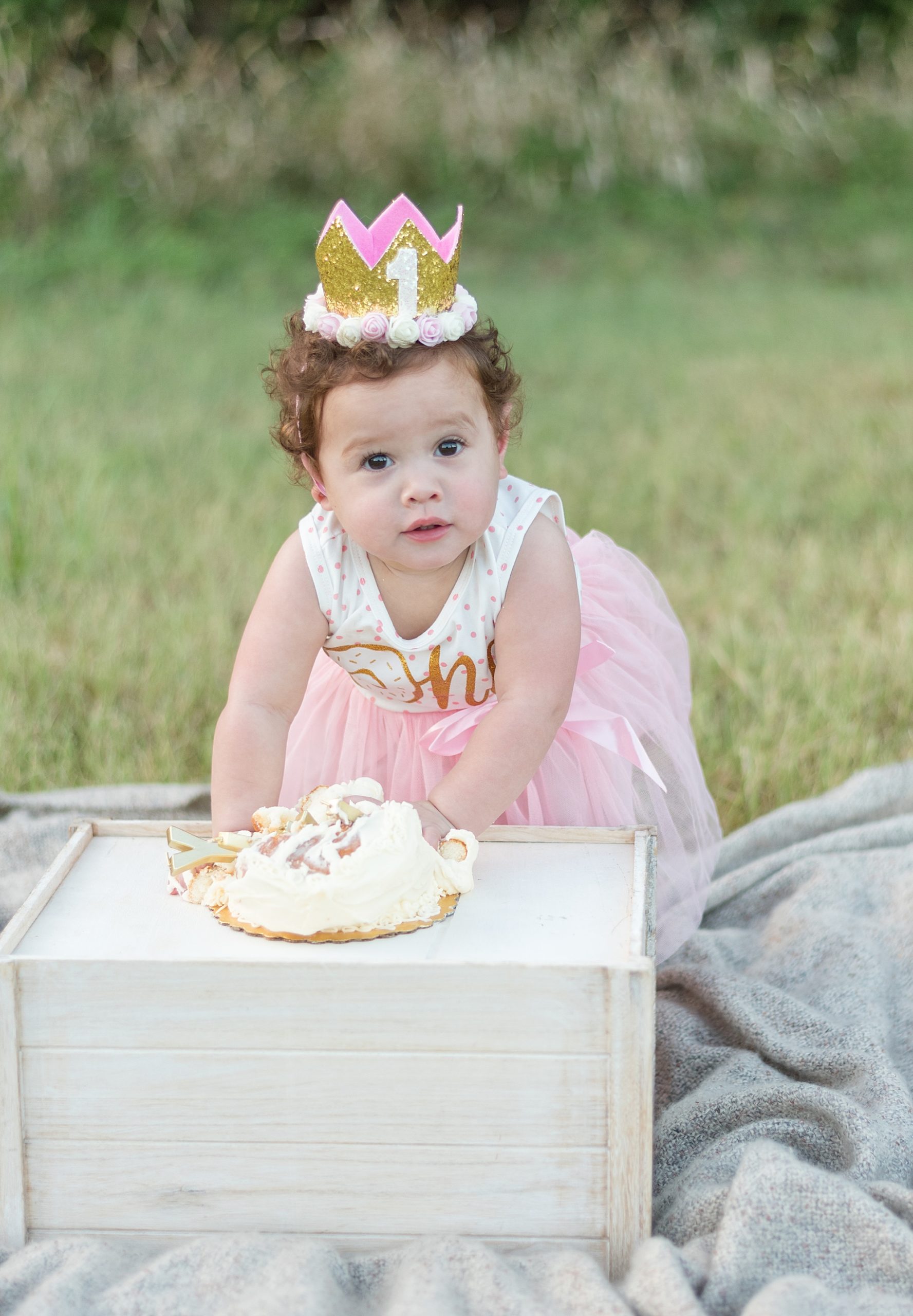 One year old holds fists of cake during cake smash