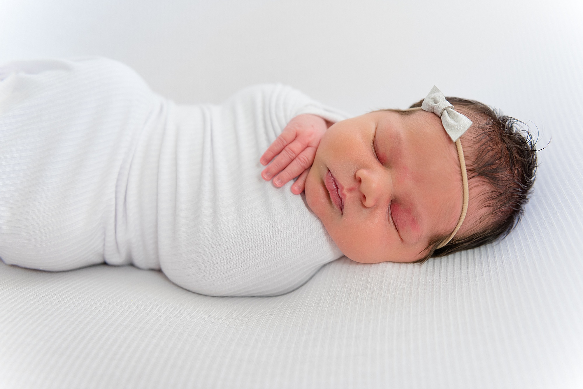 baby girl sleeps swaddled in white blanket during TX Newborn session