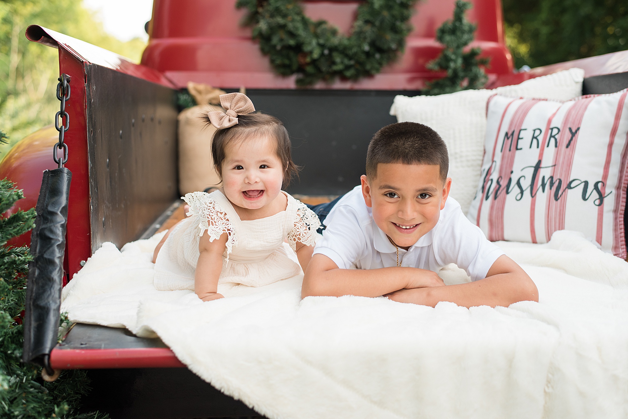 brother + sister sit in red truck for christmas family portraits in Texas