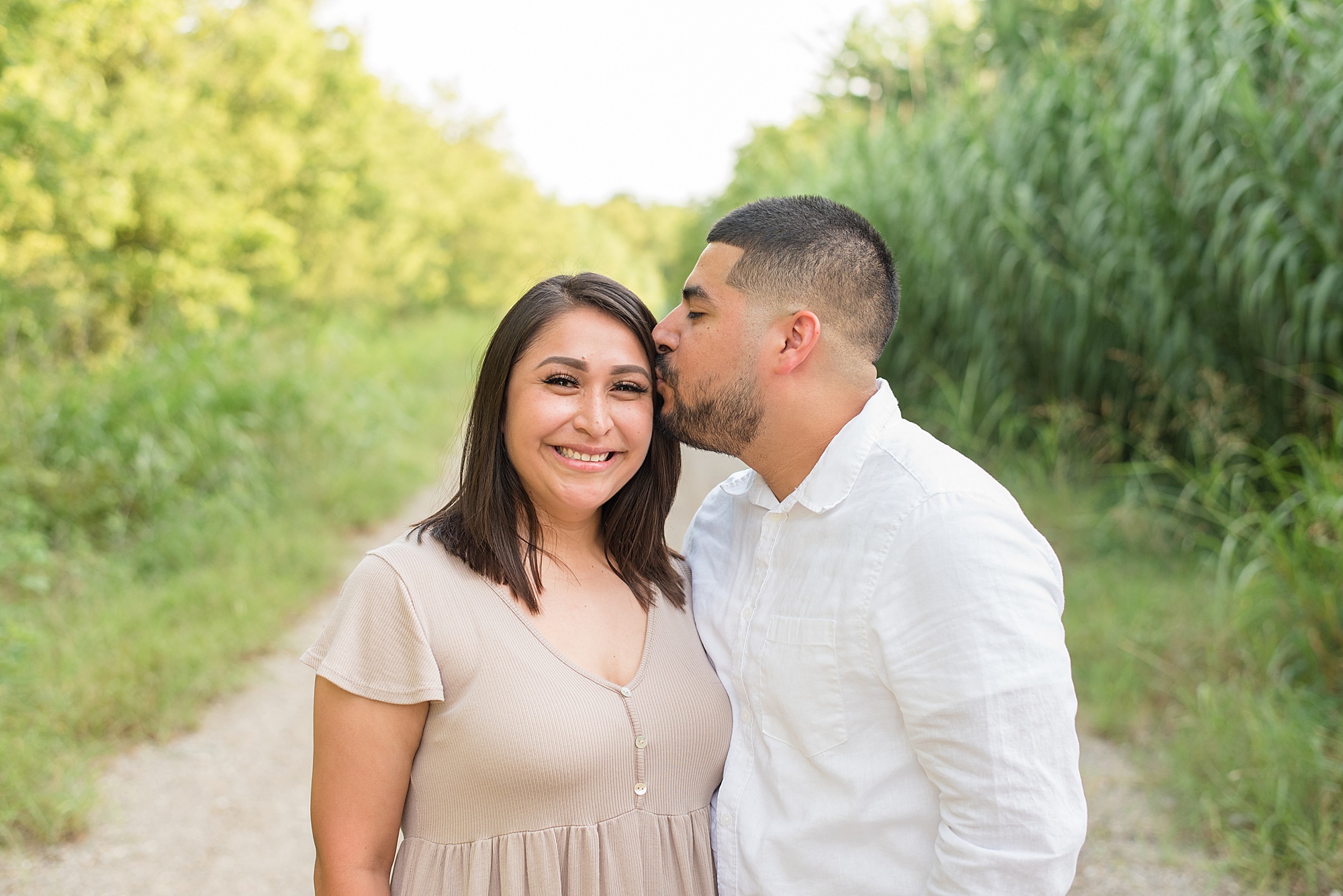 husband kisses wife cheek during little Elm Texas family portraits