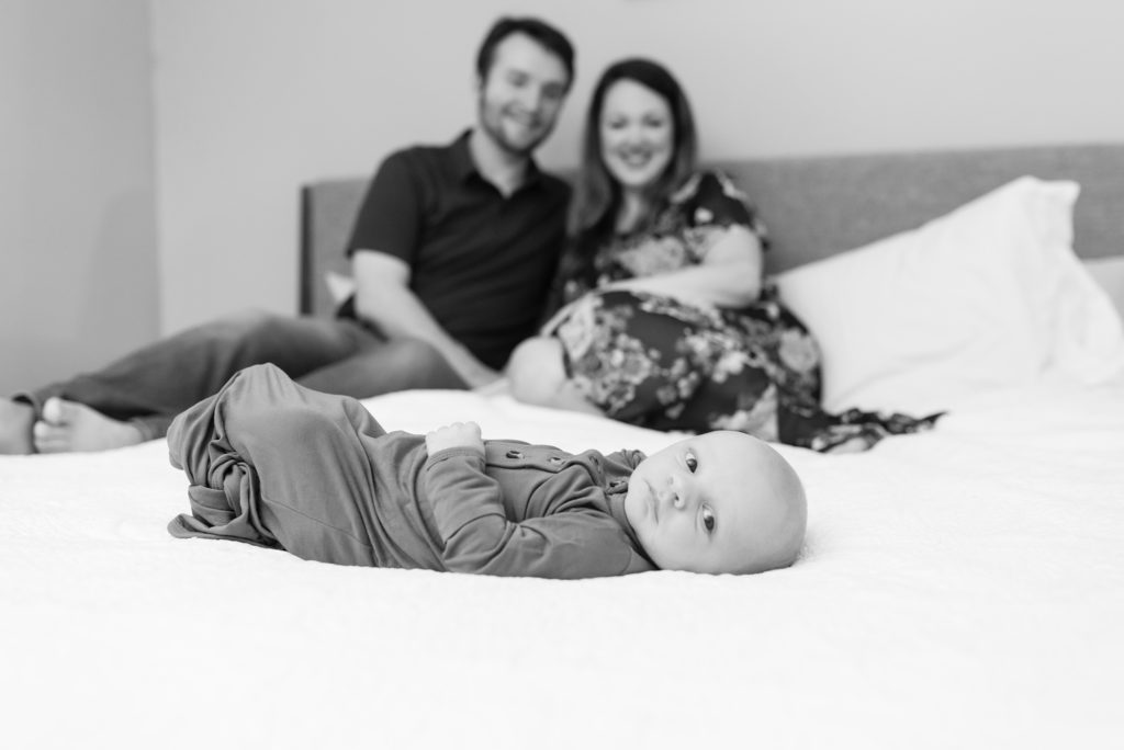 Parents sit on bed looking at their newborn sonson 