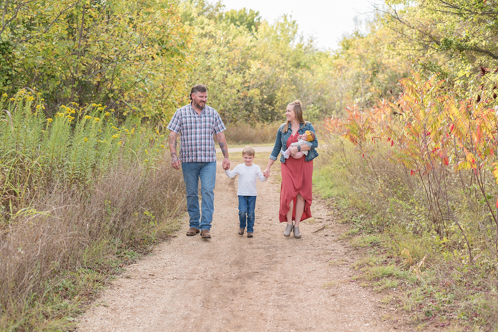 family of four walks holding hands during fall family photos