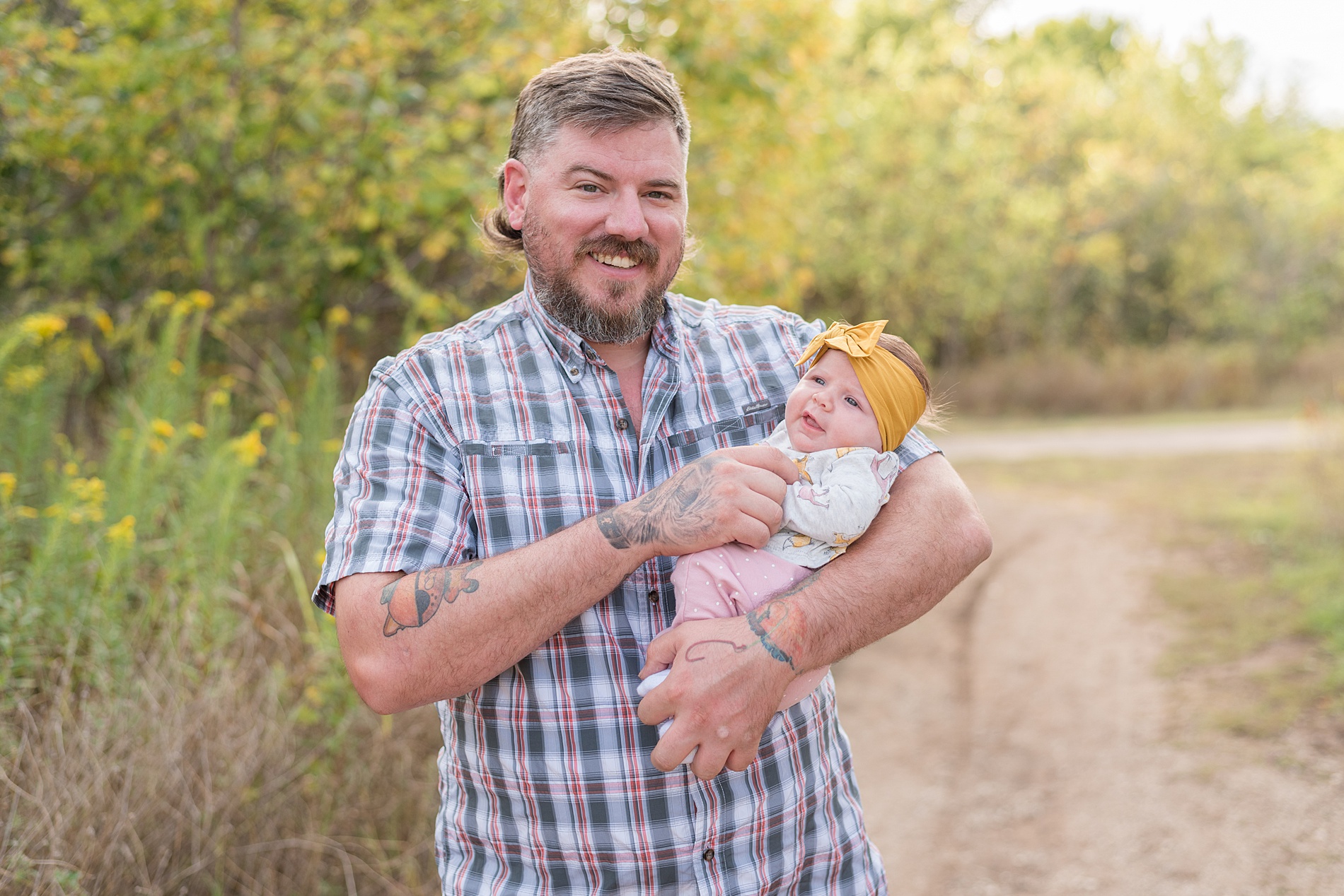 dad smiles holding his baby girl in yellow headband