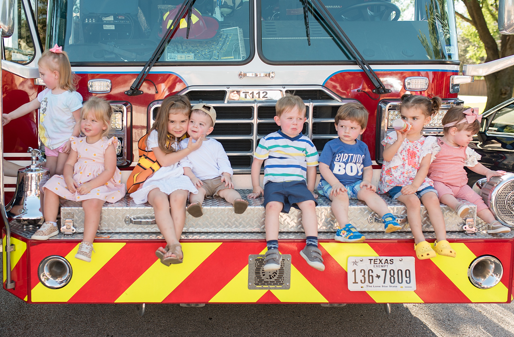little boy sits with his friends on the front of fire truck at birthday party