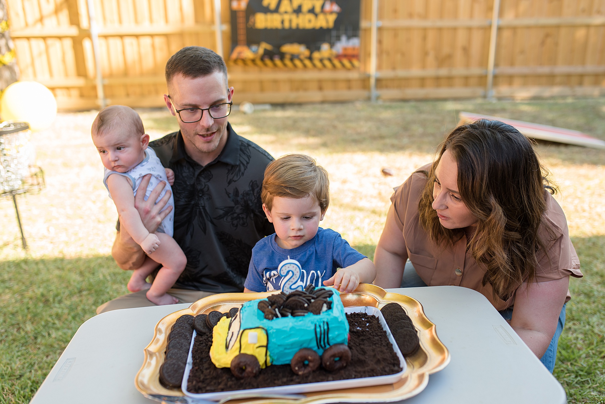 birthday boy looks at his birthday cake with his family