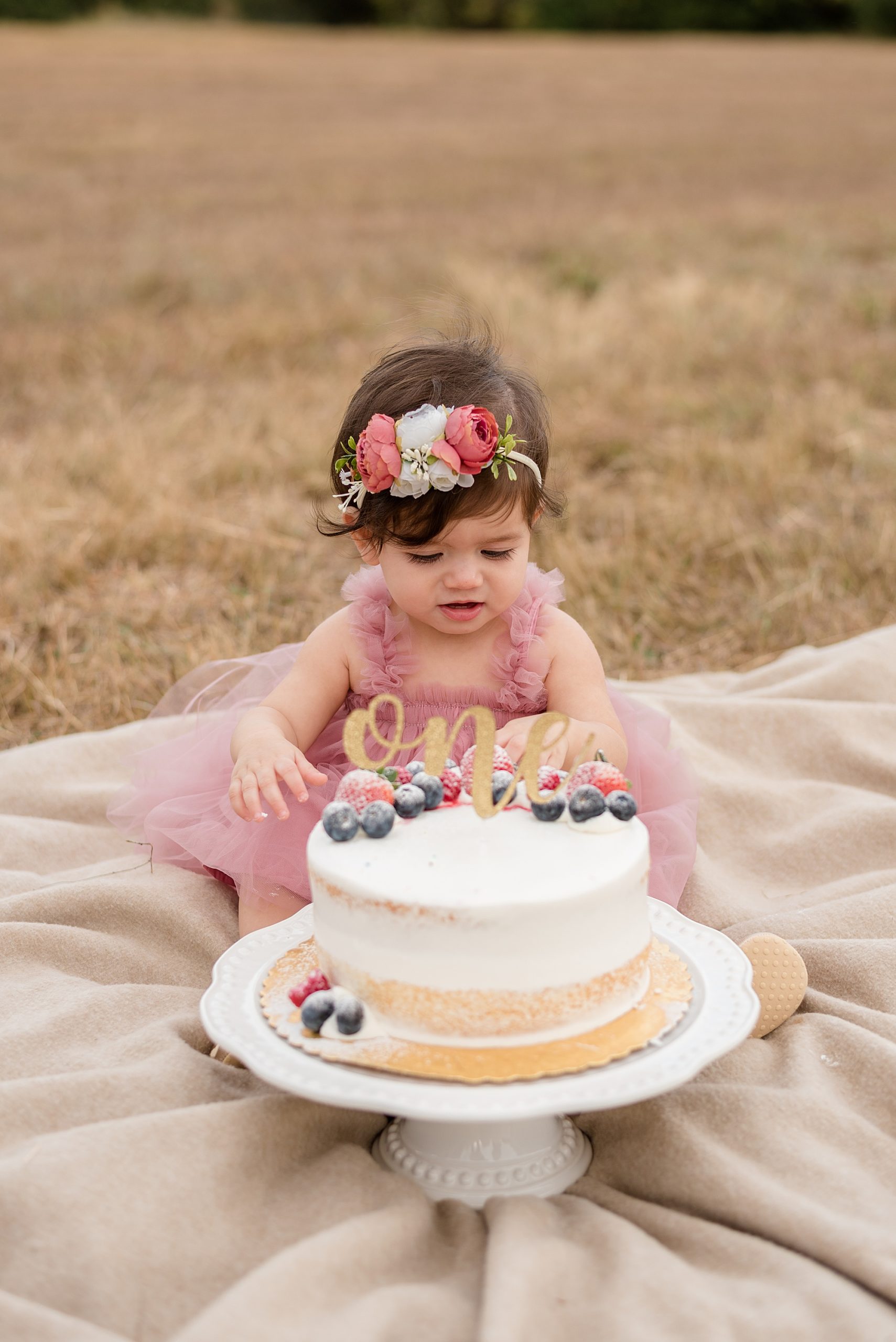birthday girl enjoys cake during cake smash at Erwin Park in Mckinney, TX