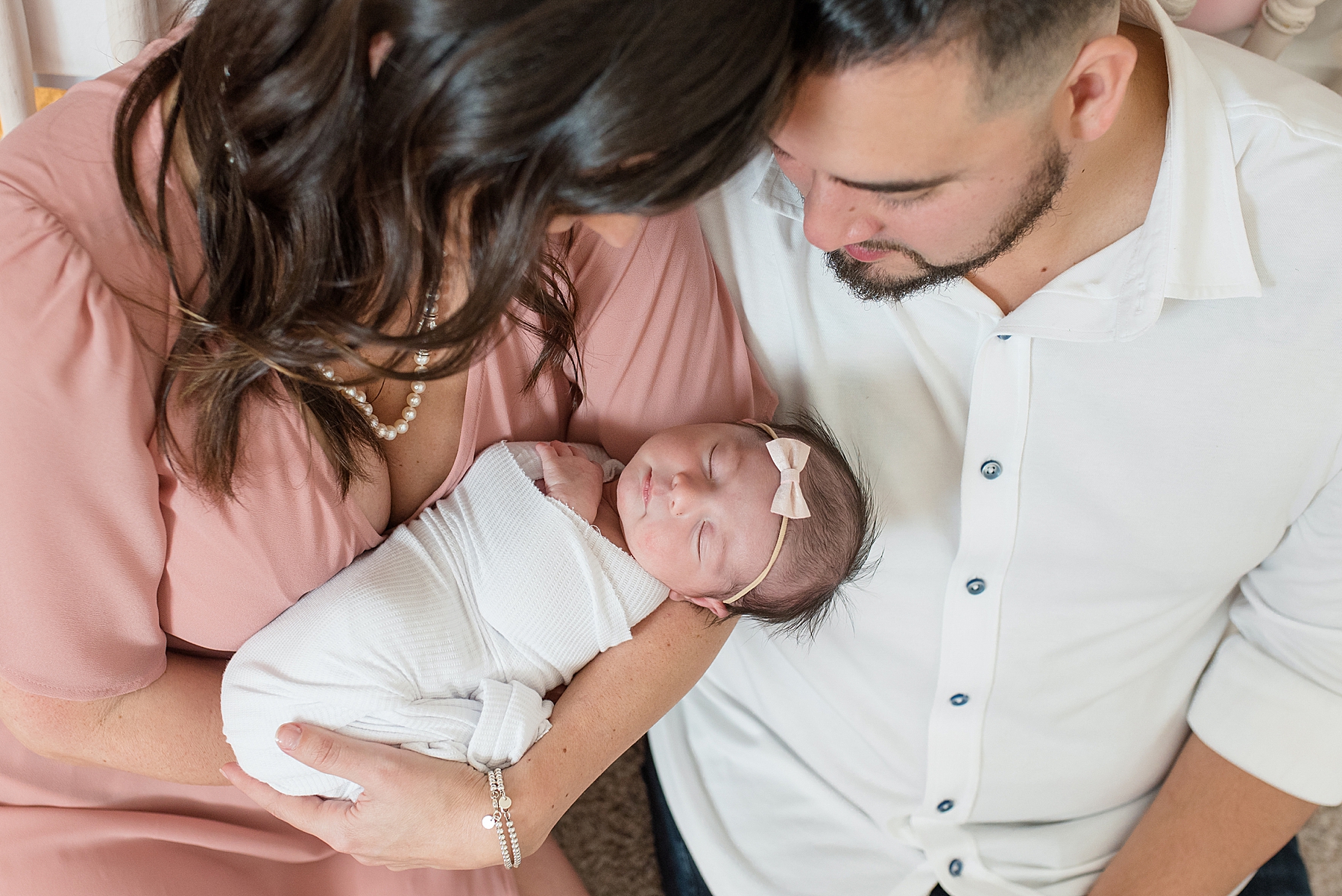 Mom in pink dressing holding newborn in white swaddle with dad arm around shoulder | Lindsey Dutton Photography | Dallas Area Family Photographer | newborn session, newborn posing ideas, newborn photos, girl nursery inspiration | via lindseyduttonphotography.com