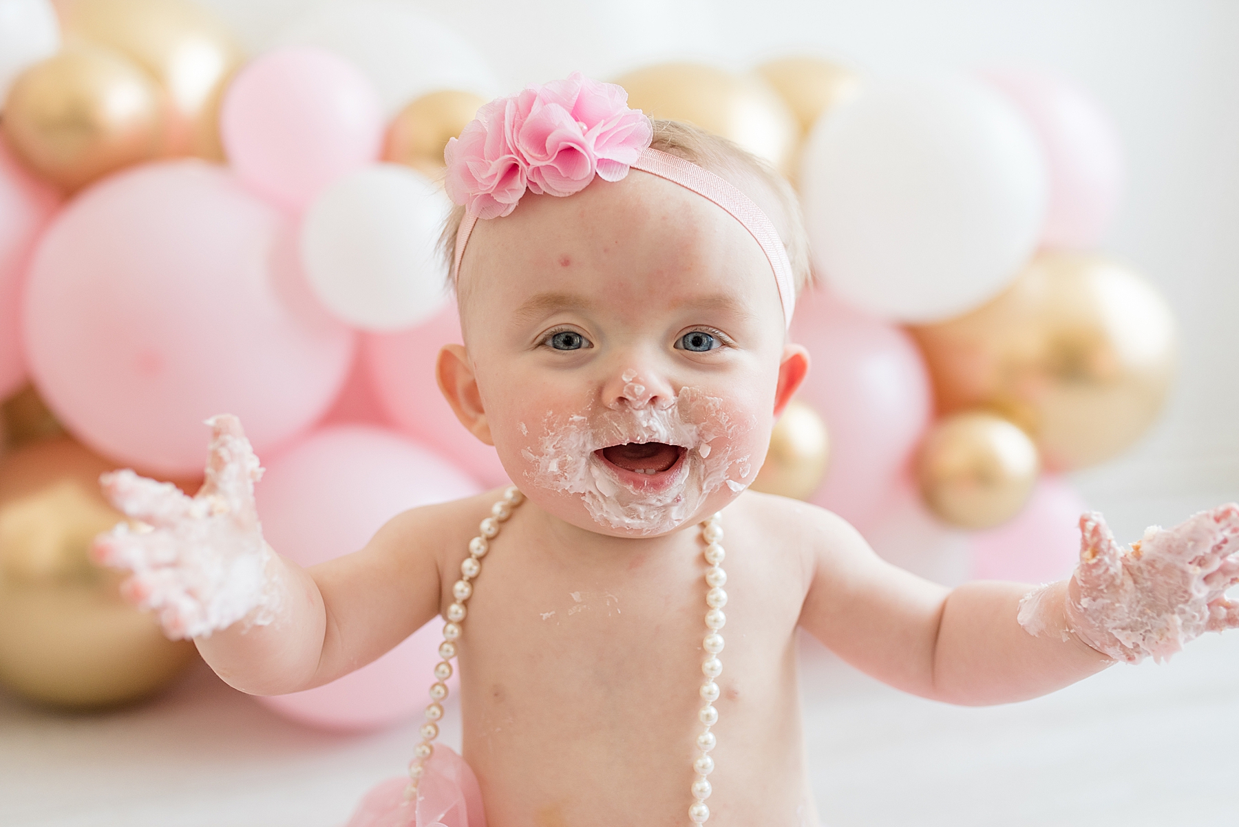 Little girl smiling with cake on her face and hands. Photographed by Dallas newborn photographer Lindsey Dutton Photography