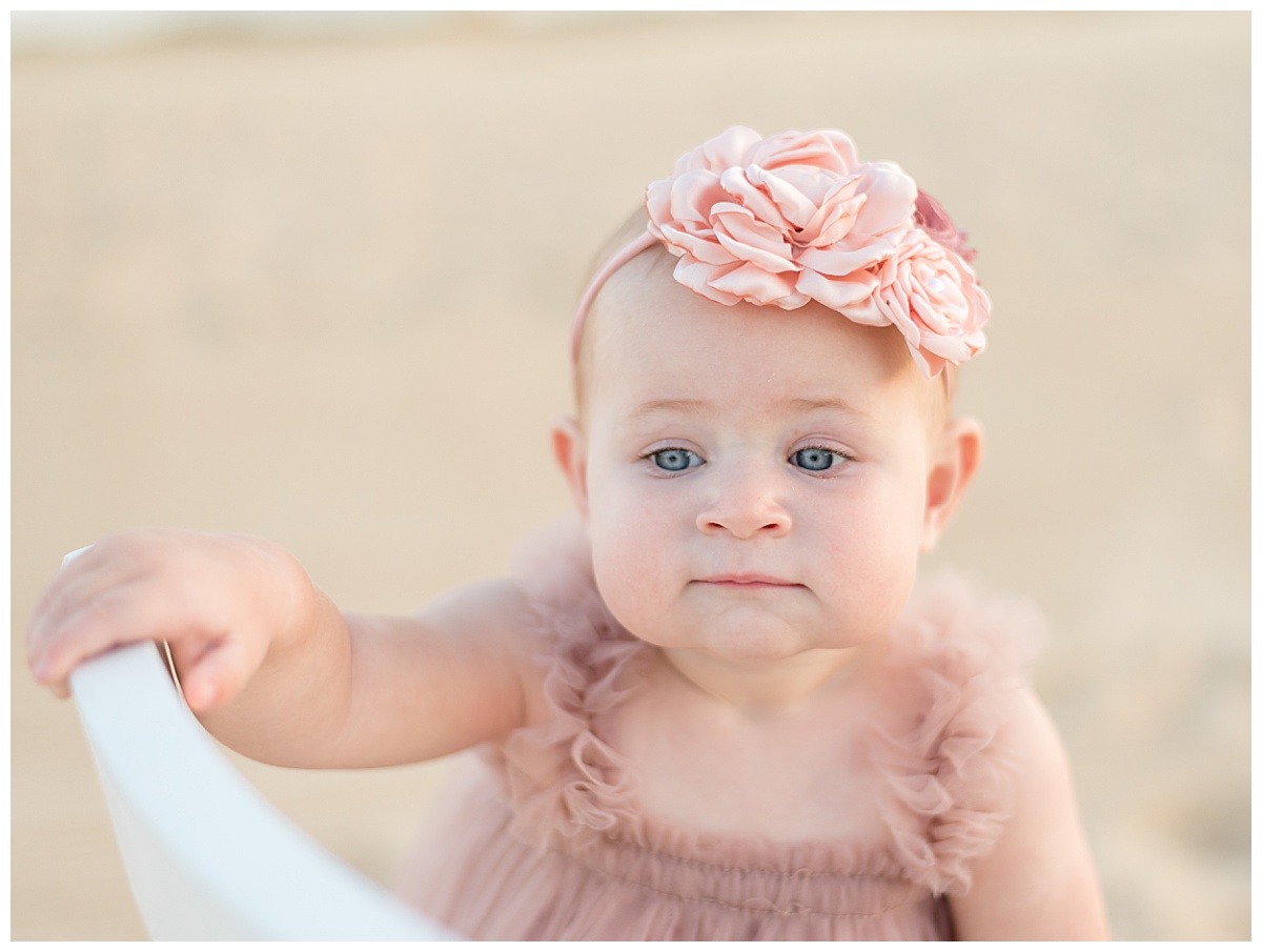 One year old girl in floral headband and pink tulle dress for her cake smash pictures in North Dallas by Lindsey Dutton Photography, a Dallas Cake Smash Photographer. 