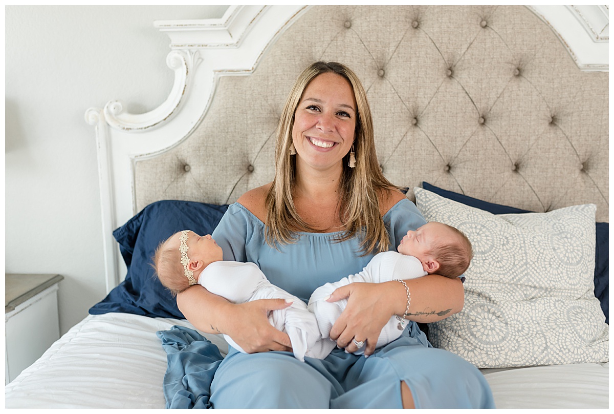 Mom holds newborn twin boy and girl on the bed for their in-home twin newborn portraits taken by Lindsey Dutton Photography, a Dallas Newborn Photographer.