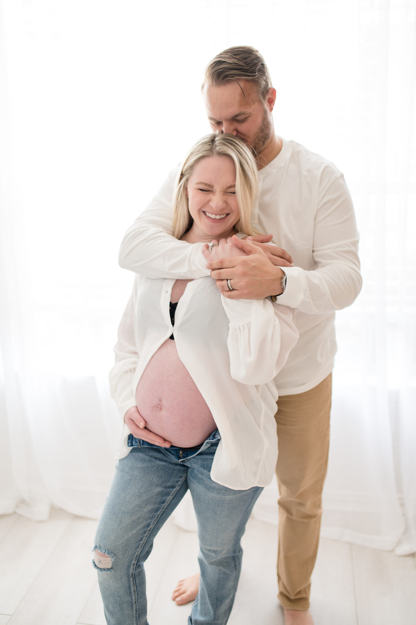 husband touches wife's pregnant belly while laughing photographed by Dallas newborn photographer, Lindsey Dutton Photography