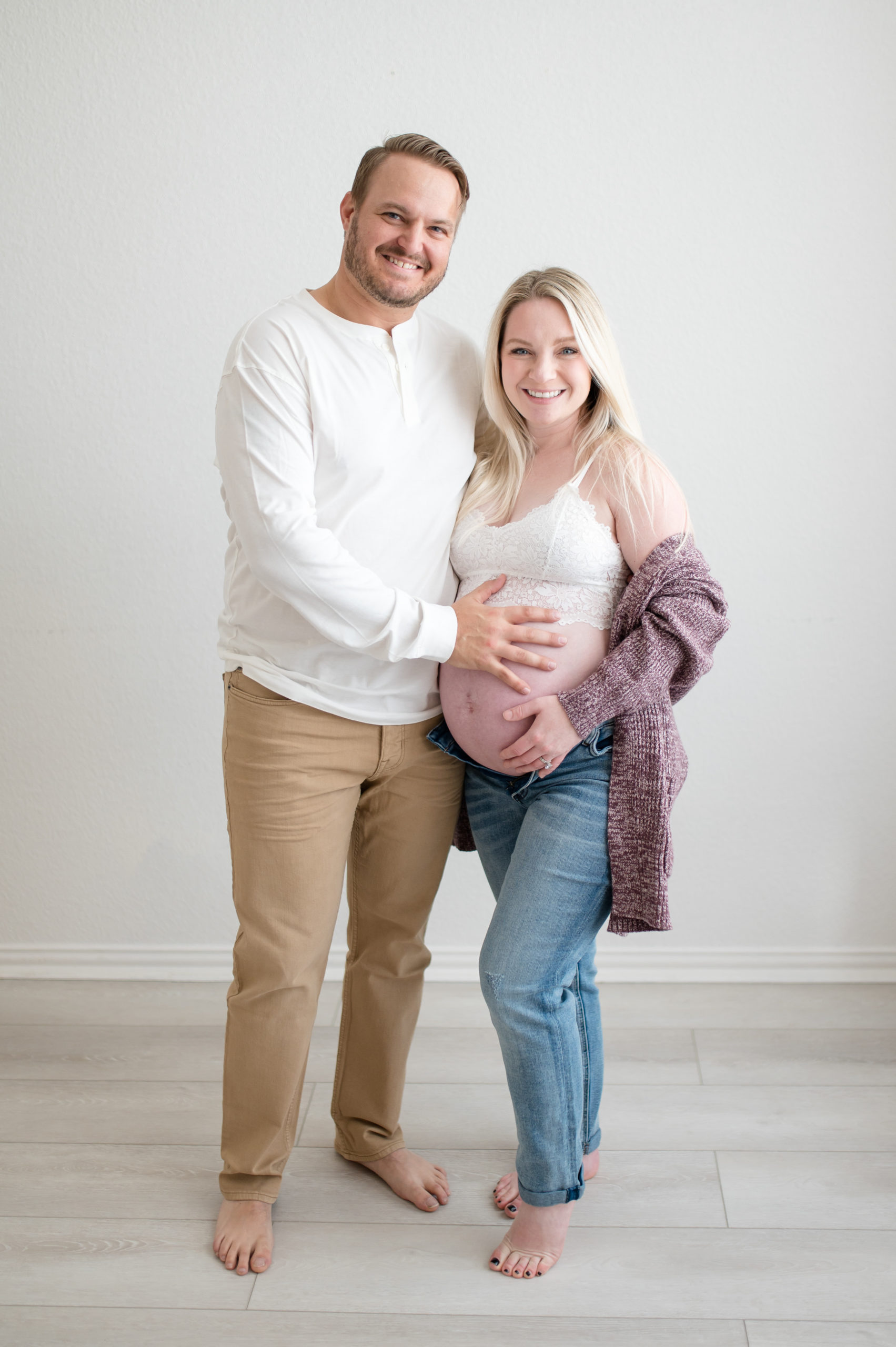husband and wife smiling holding baby bump during an in studio maternity session in dallas texas photographed by Dallas newborn photographer, Lindsey Dutton Photography