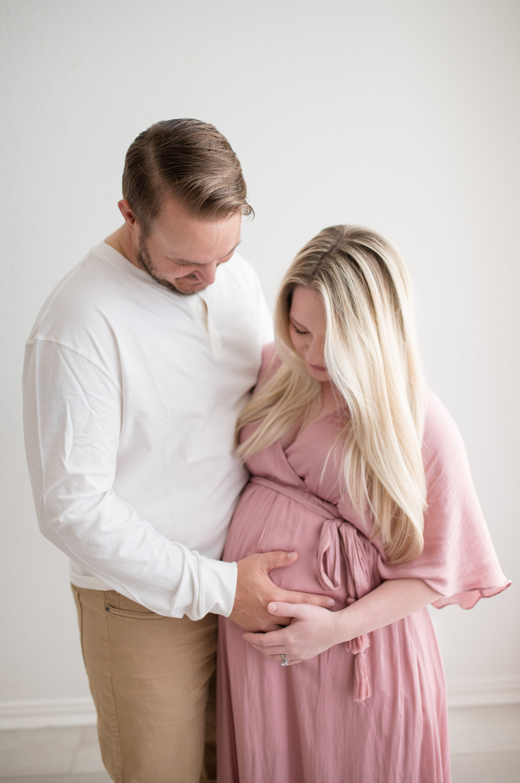 Couple embracing belly at a studio in Dallas Texas photographed by Dallas newborn photographer, Lindsey Dutton Photography