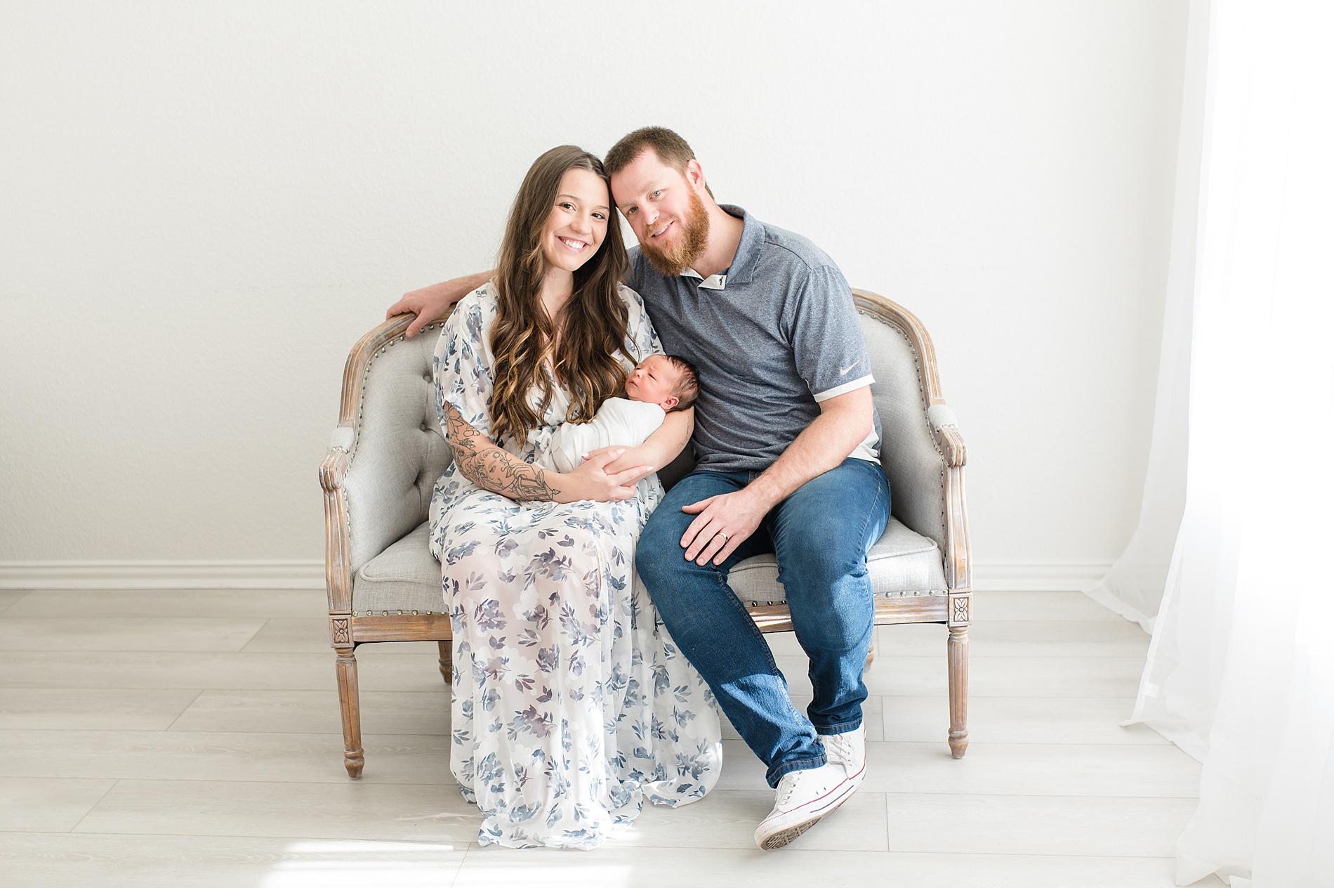 family of three sit on bench during Studio Newborn Session 