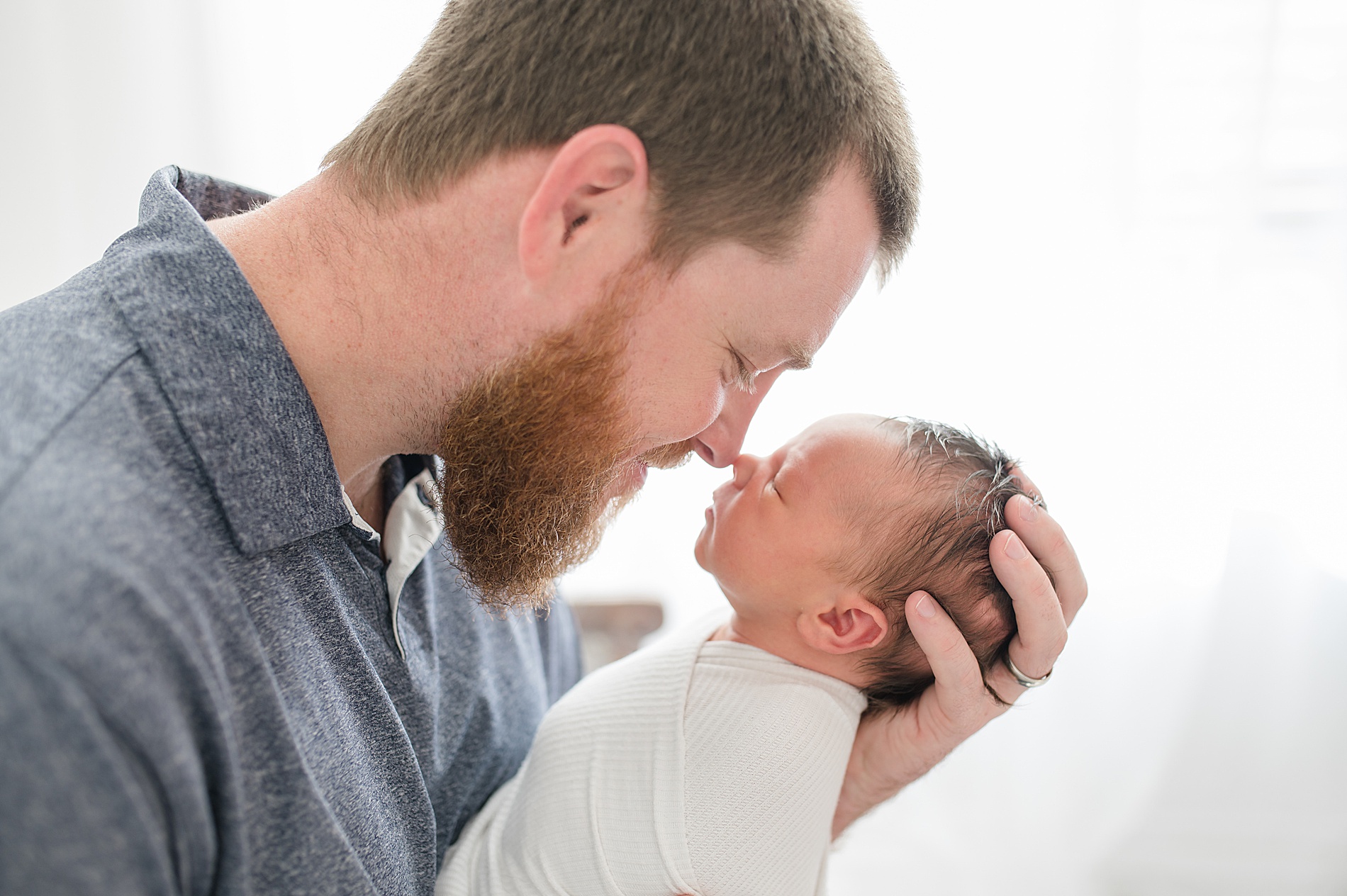 dad leans down and touches newborn's nose