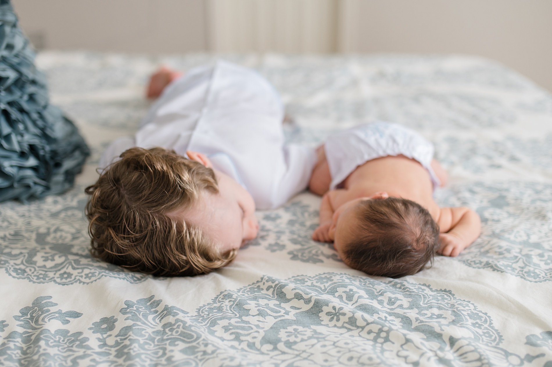 brothers laying on bed looking at each other taken by Lindsey Dutton Photography, a Dallas Newborn photographer