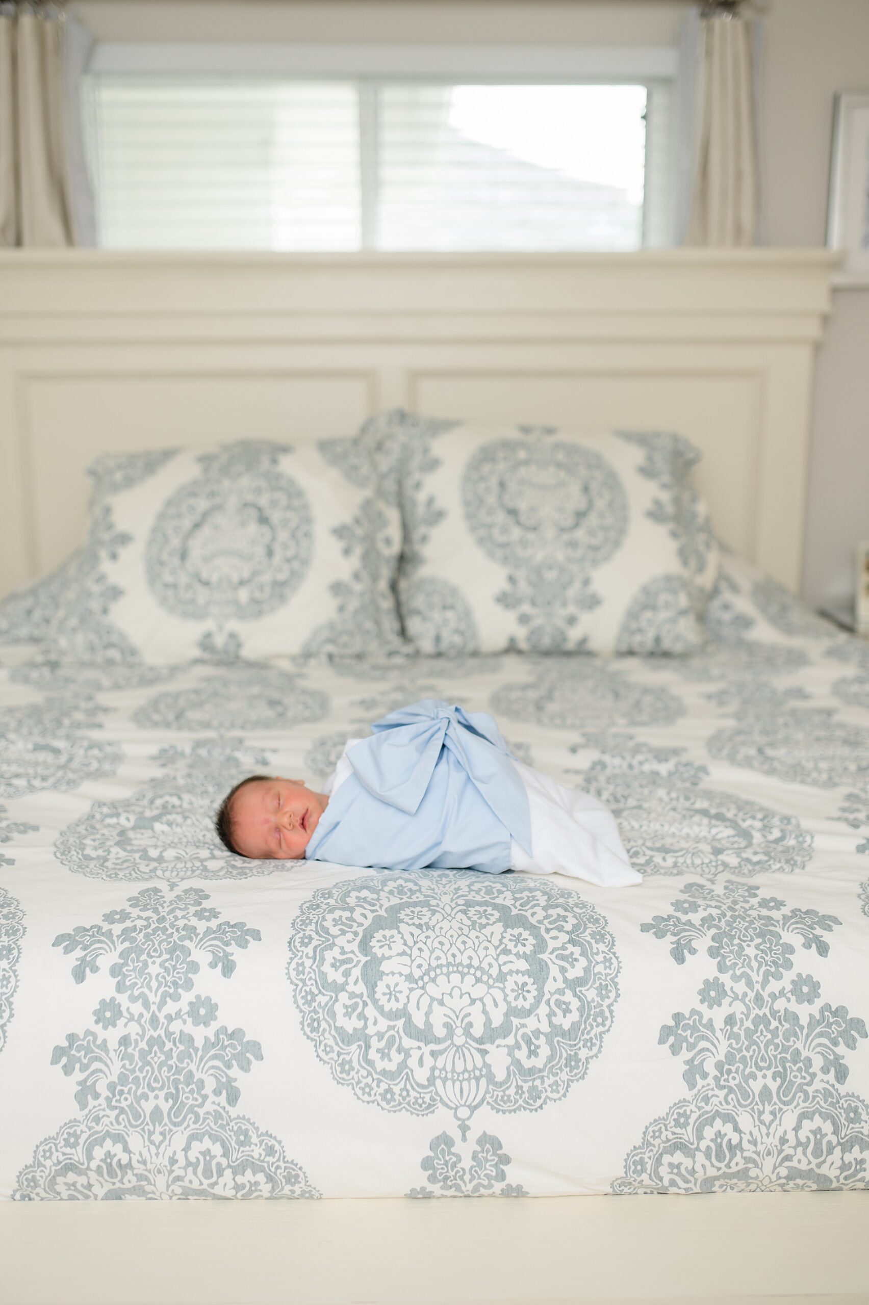 newborn baby in beaufort bonnet swaddle on bed photographed by Lindsey Dutton Photography, a Dallas Newborn photographer