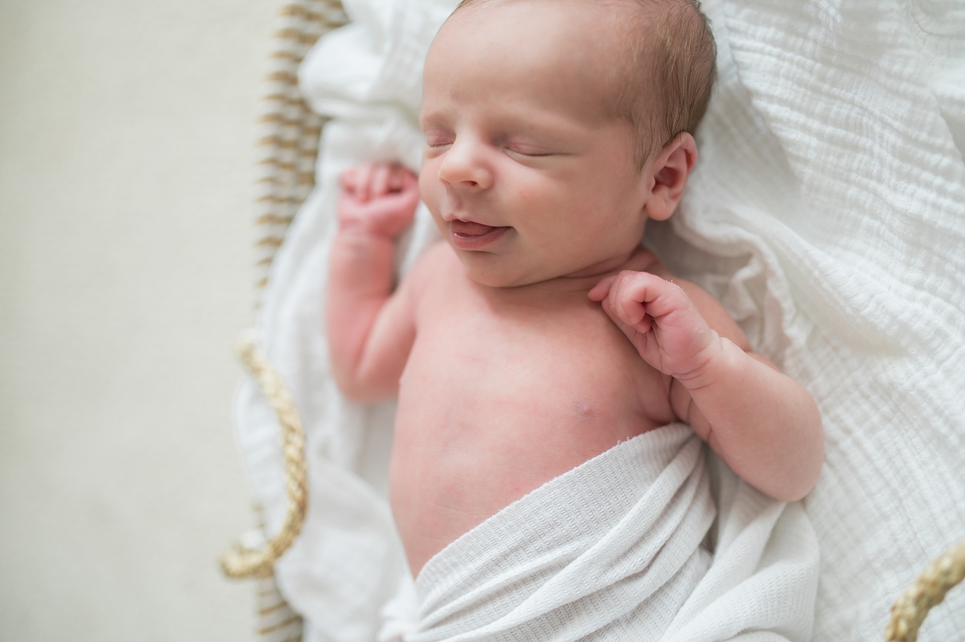 newborn gives sleepy smile in bassinet by Lindsey Dutton Photography, Dallas Newborn photographer