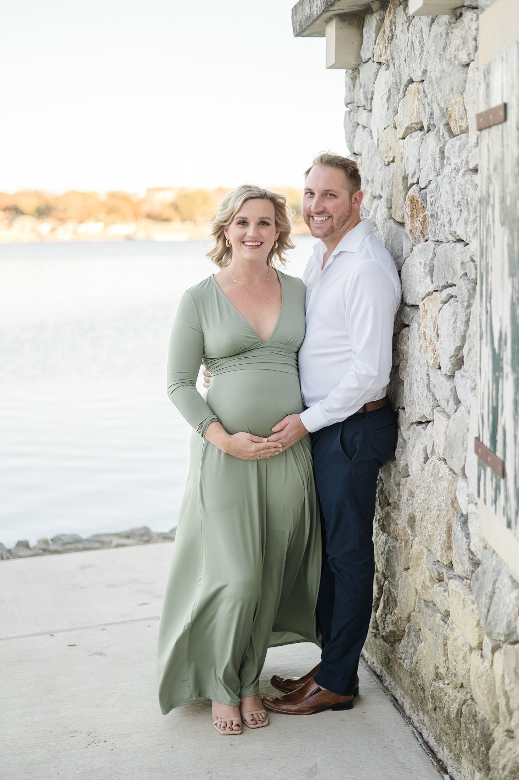 expectant parents lean against stone wall taken by Lindsey Dutton Photography, a Dallas Family photographer
