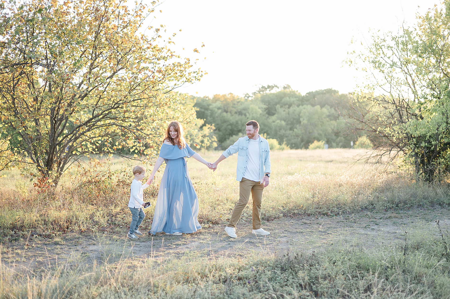 family of three walks together during maternity session taken by Lindsey Dutton Photography, a Dallas maternity photographer
