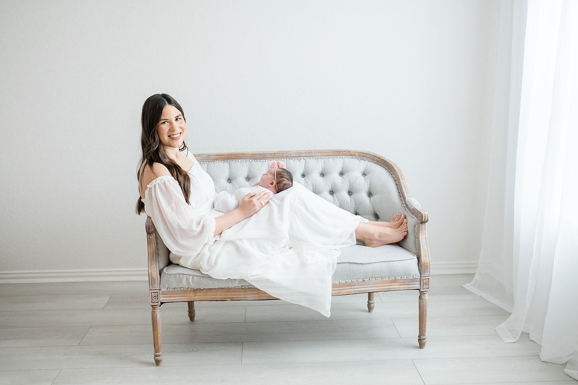 mom on couch holding newborn girl photographed by Lindsey Dutton Photography, a Dallas newborn photographer
