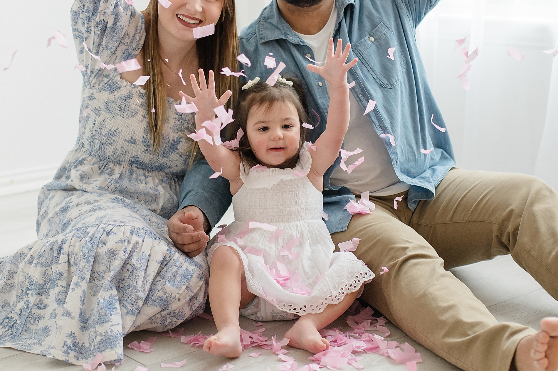 excited family tosses the pink confetti from their gender reveal session photographed by Lindsey Dutton Photography, a Dallas Maternity photographer