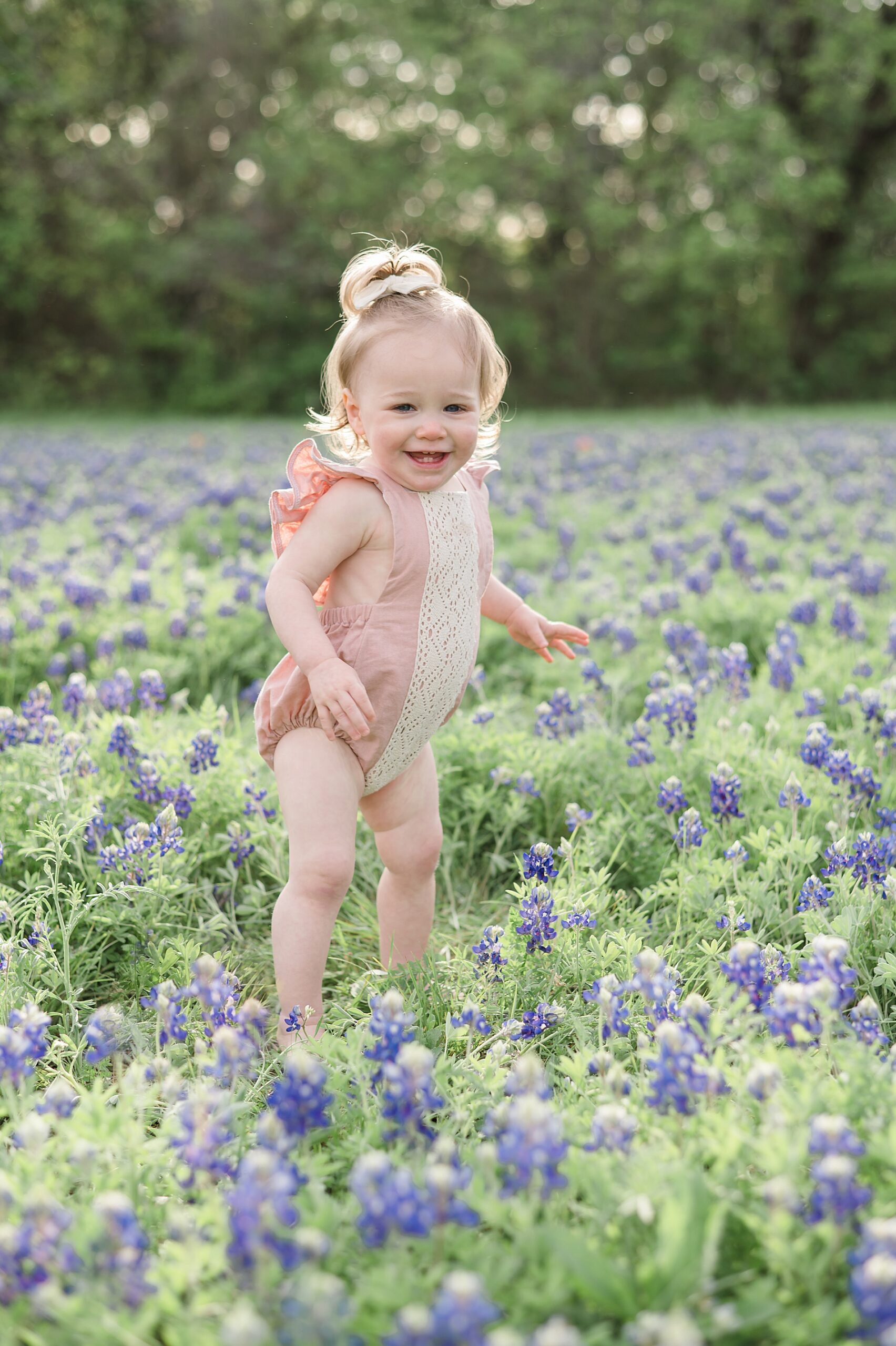 toddler girl stands in field of Bluebonnet flowers photographed by Lindsey Dutton Photography, a Dallas family photographer