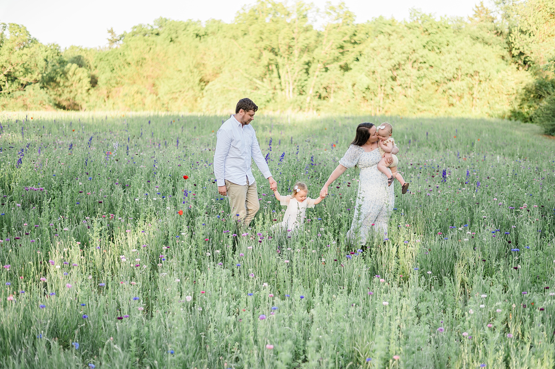 family of four hold hands walking through field of wildflowers taken by Lindsey Dutton Photography, a Dallas family photographer
