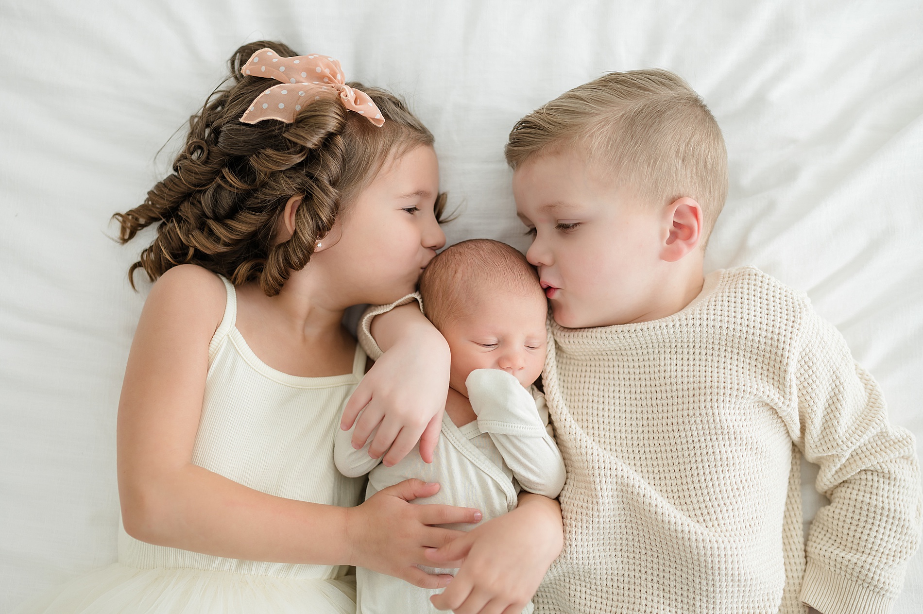 How to Prepare Siblings For Newborn Photos | Older siblings kiss their newborn brother's head photographed by Lindsey Dutton Photography, a Dallas newborn photographer
