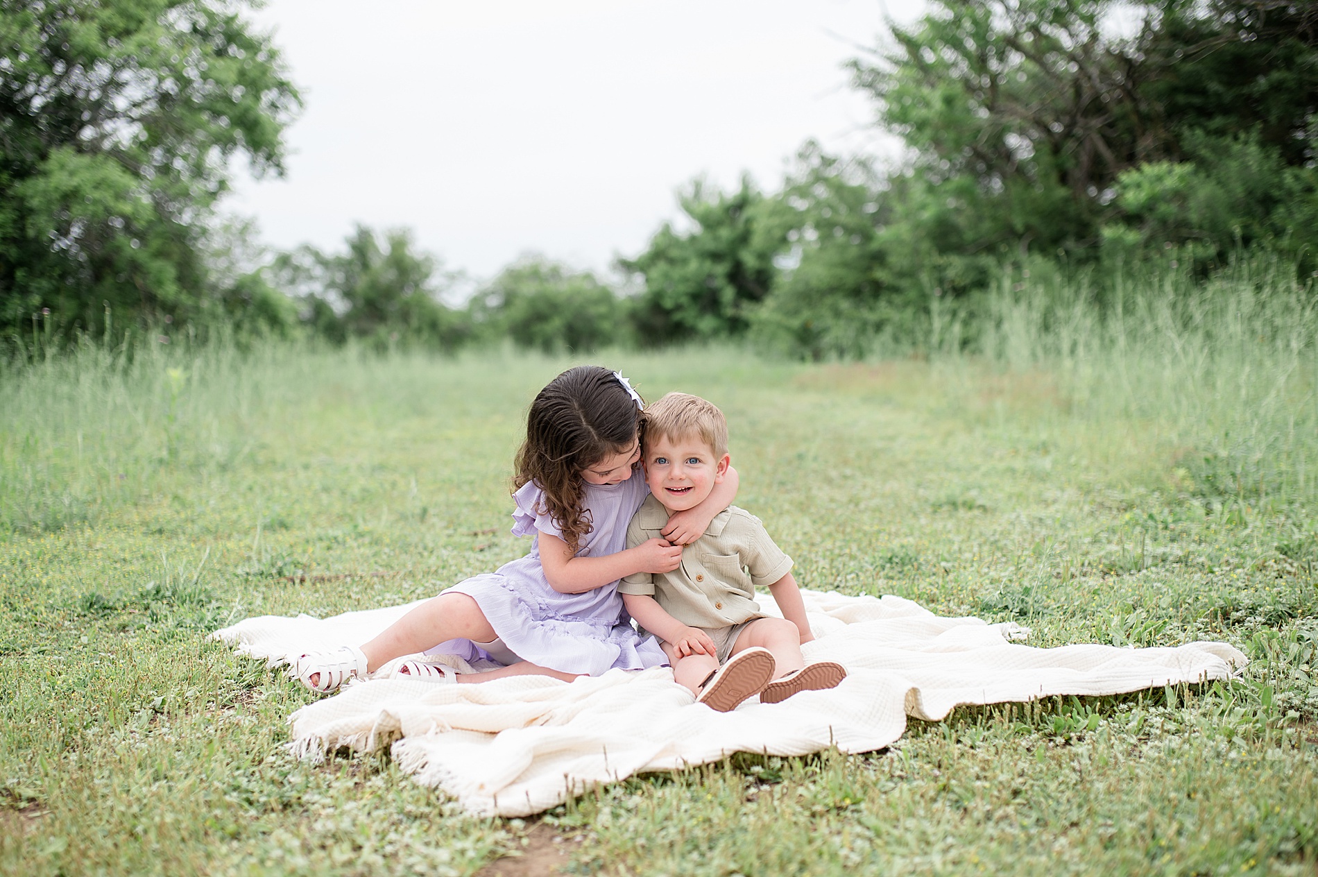 siblings hug while sitting on blanket taken by Lindsey Dutton Photography, a Dallas family photographer
