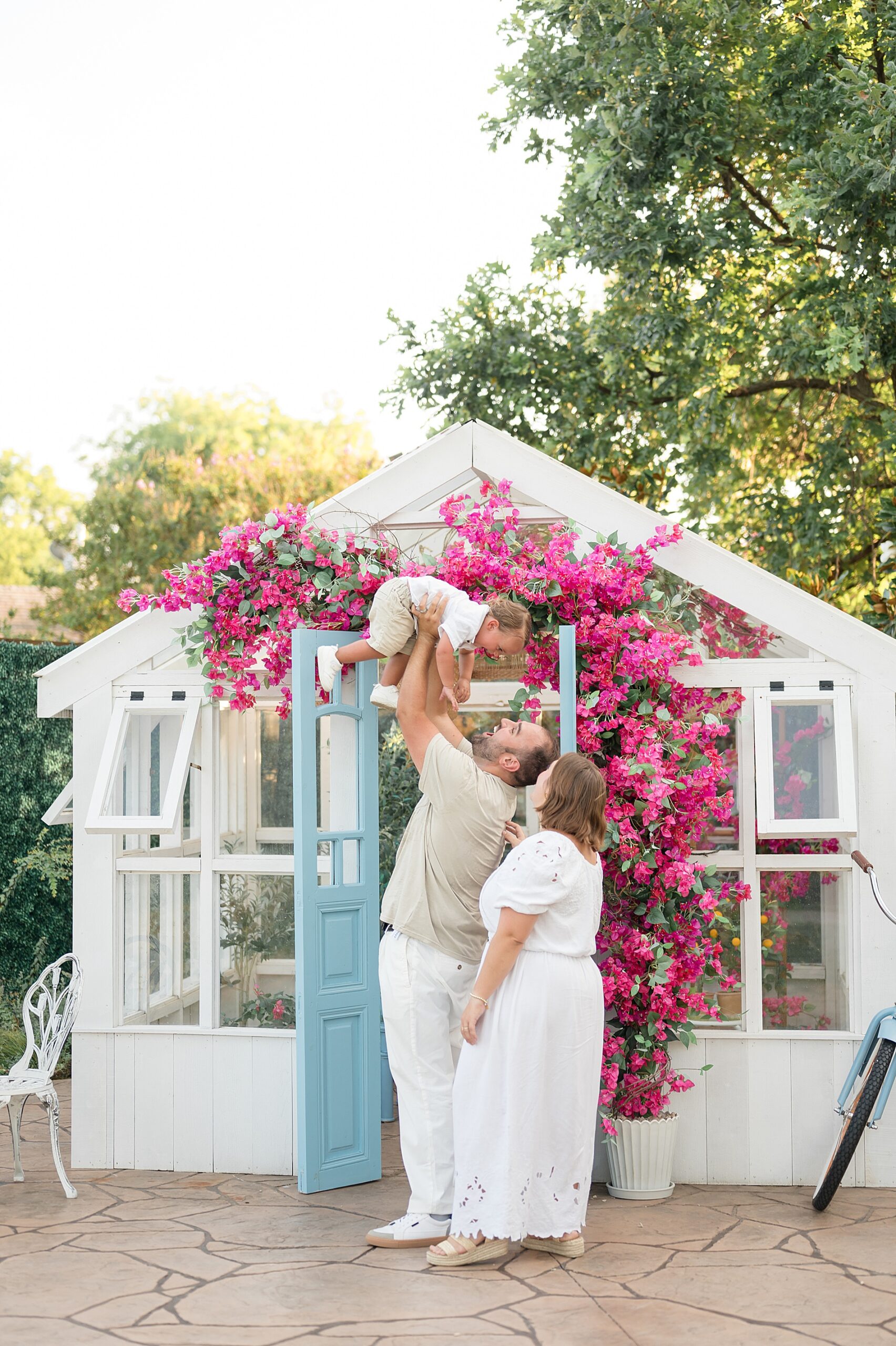 family of three in front of greenhouse at Lemon drop studios taken by Lindsey Dutton Photography, a Dallas Family photographer
