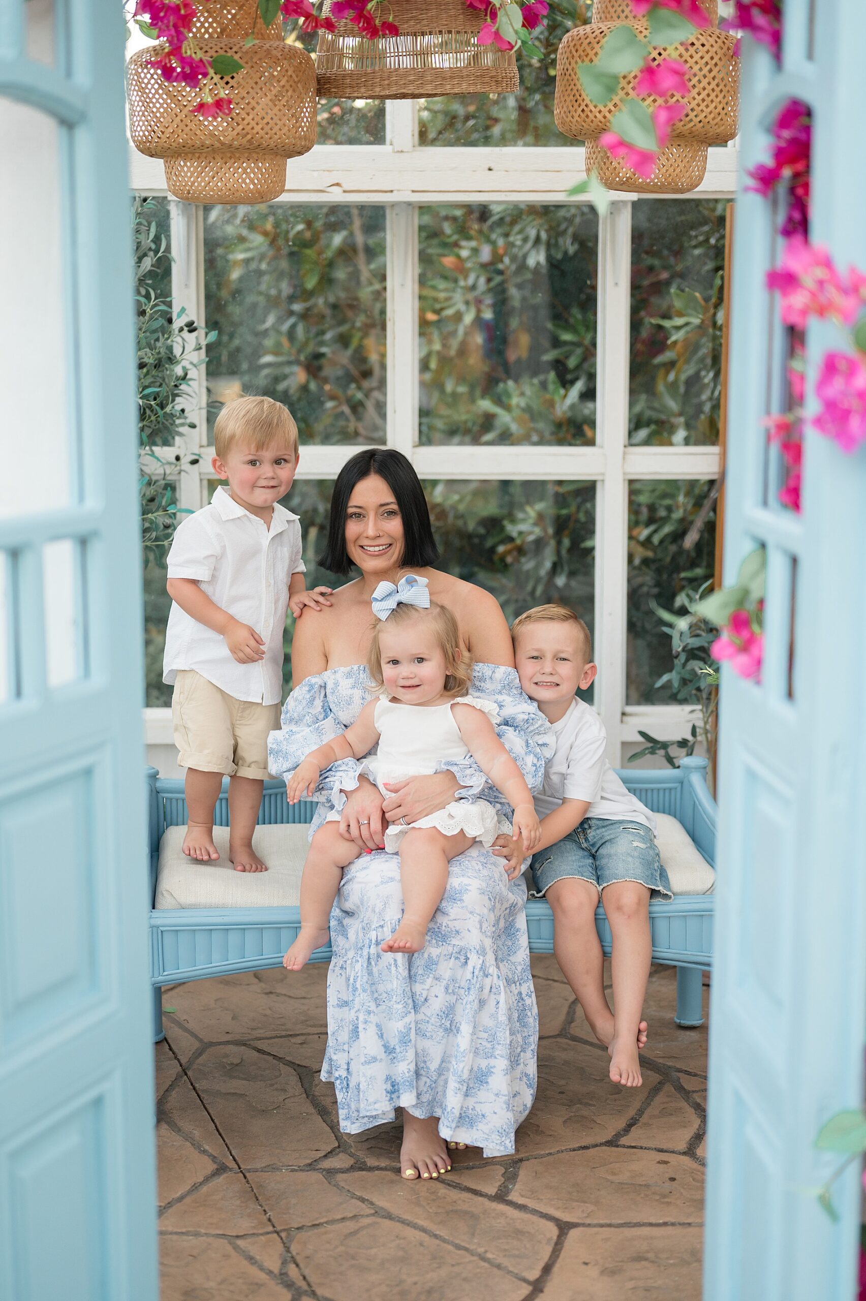 Mom with three kids sit inside adorable greenhouse photographed by Lindsey Dutton Photography, a Dallas Family photographer
