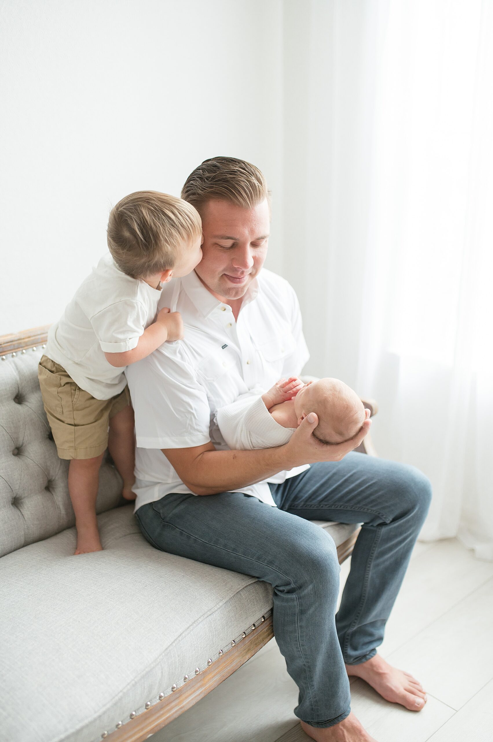 dad holds newborn boy while big brother looks on photographed by Lindsey Dutton Photography, a Dallas Newborn photographer