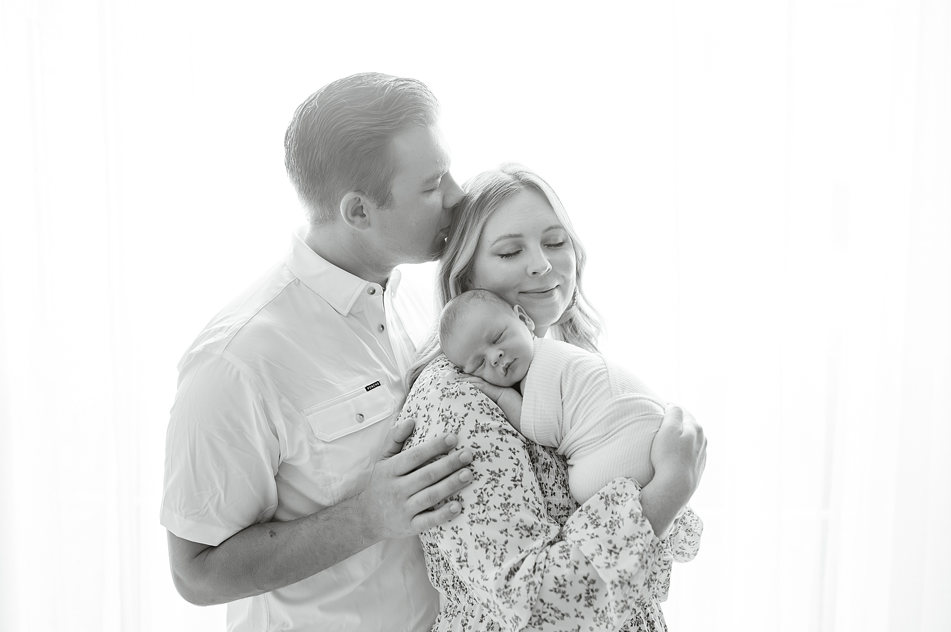 dad kisses mom's head while holding newborn photographed by Lindsey Dutton Photography, a Dallas Newborn photographer