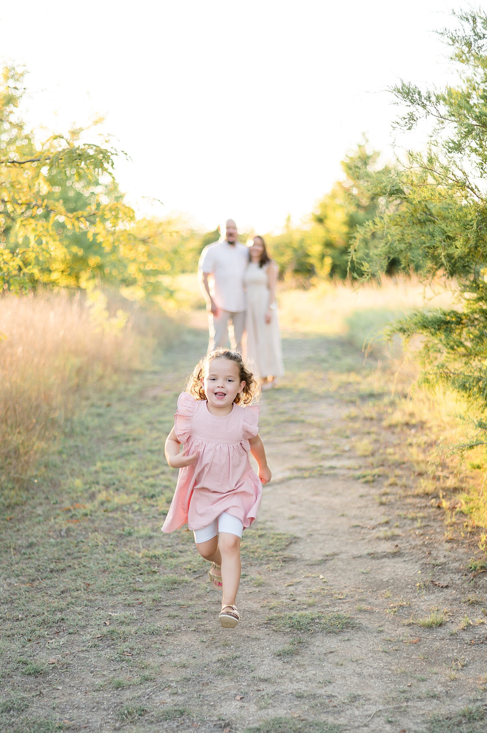 parents walk together as little girl runs ahead photographed by Lindsey Dutton Photography, a Dallas Family photographer
