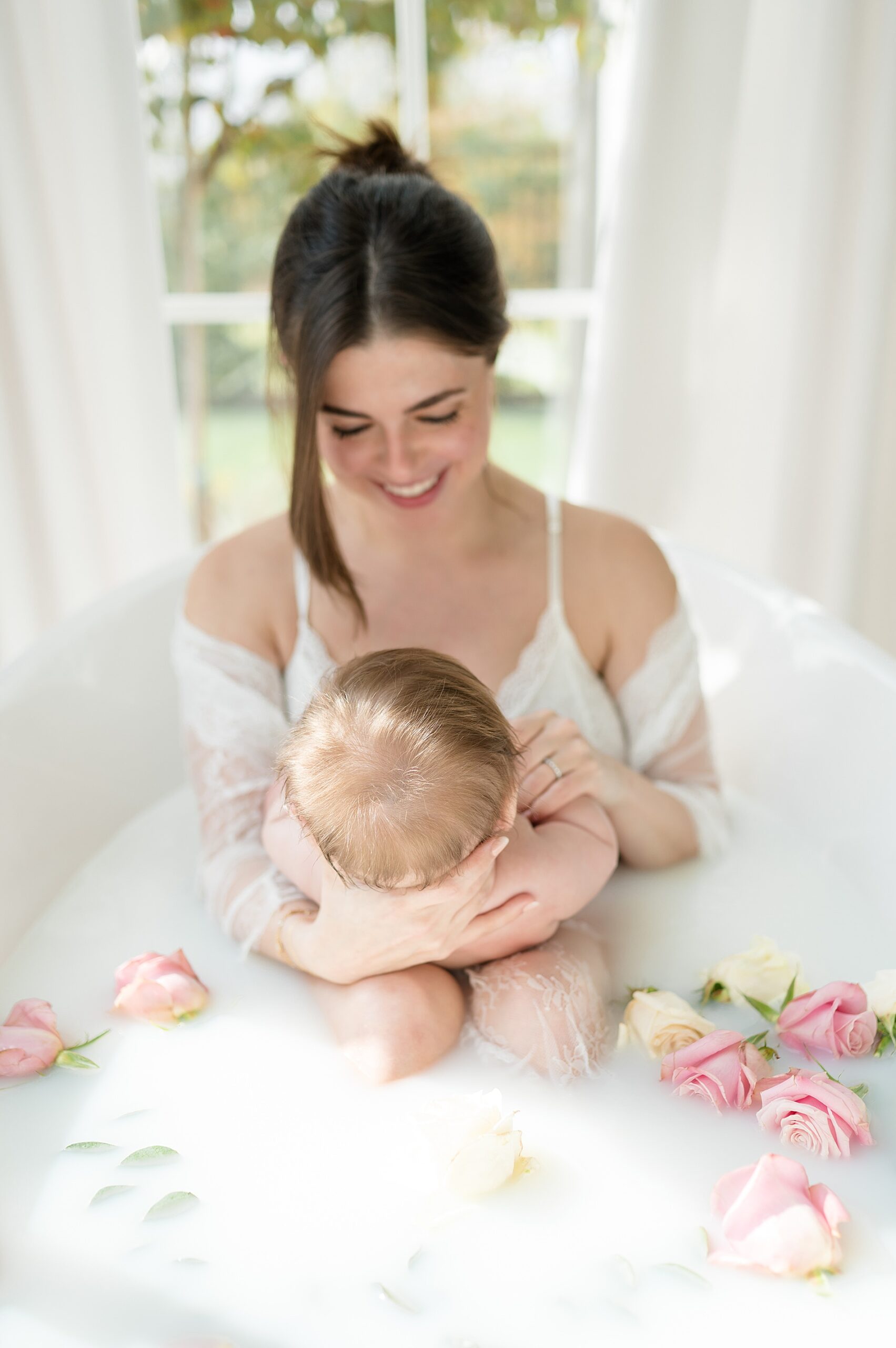 candid photo of mom looking down at baby in milk bath | Milestone photography