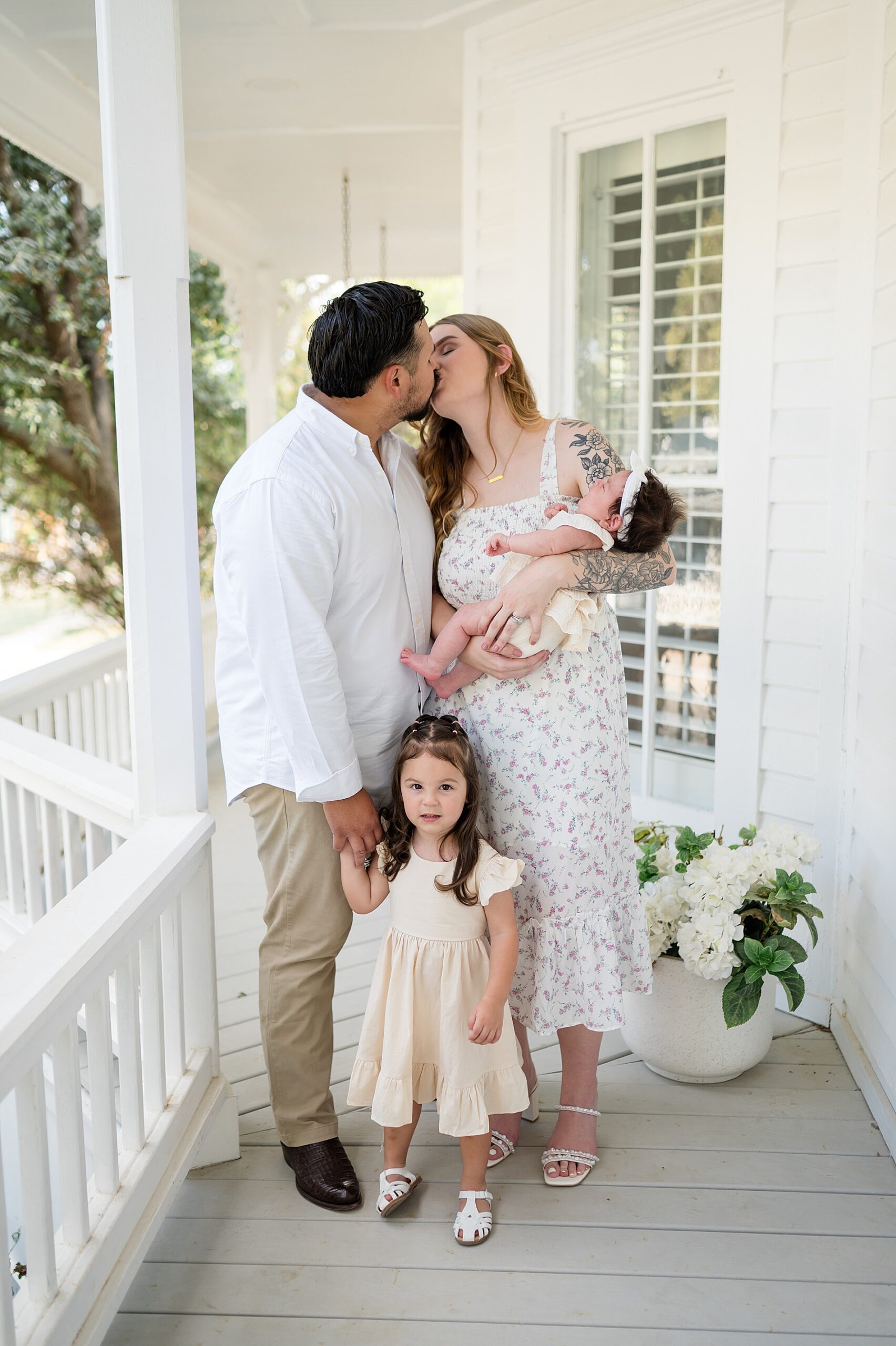 parents kiss with their two little girls nearby in McKinney, Texas