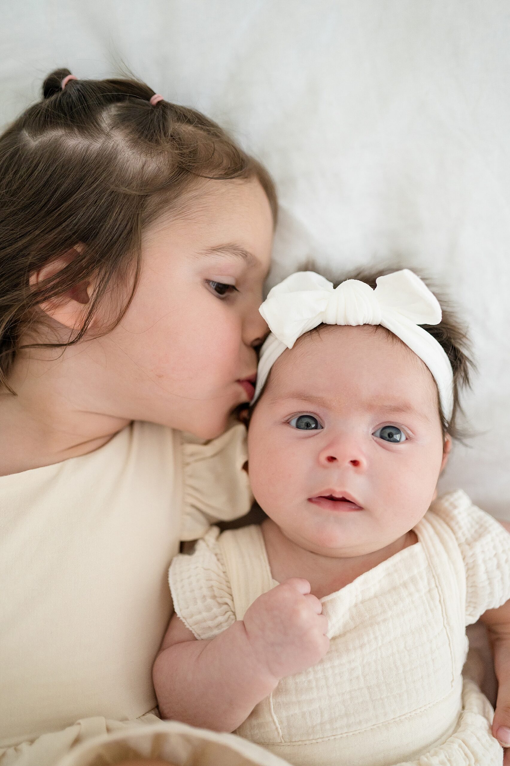 big sister kisses baby sisters head | Newborn photographer in McKinney, Texas