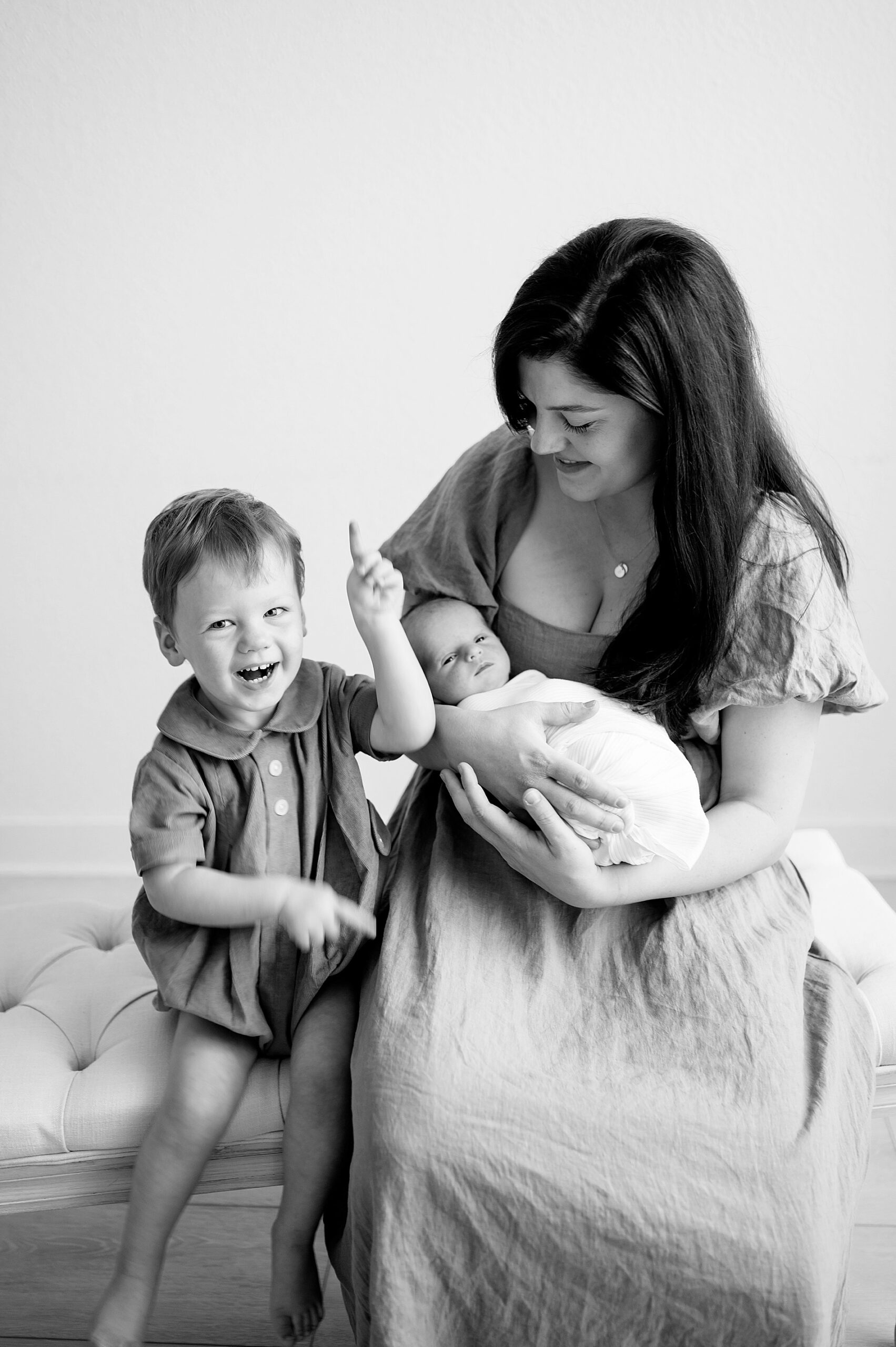 mom holds newborn with older son sitting next to her by Dallas newborn lifestyle photographer