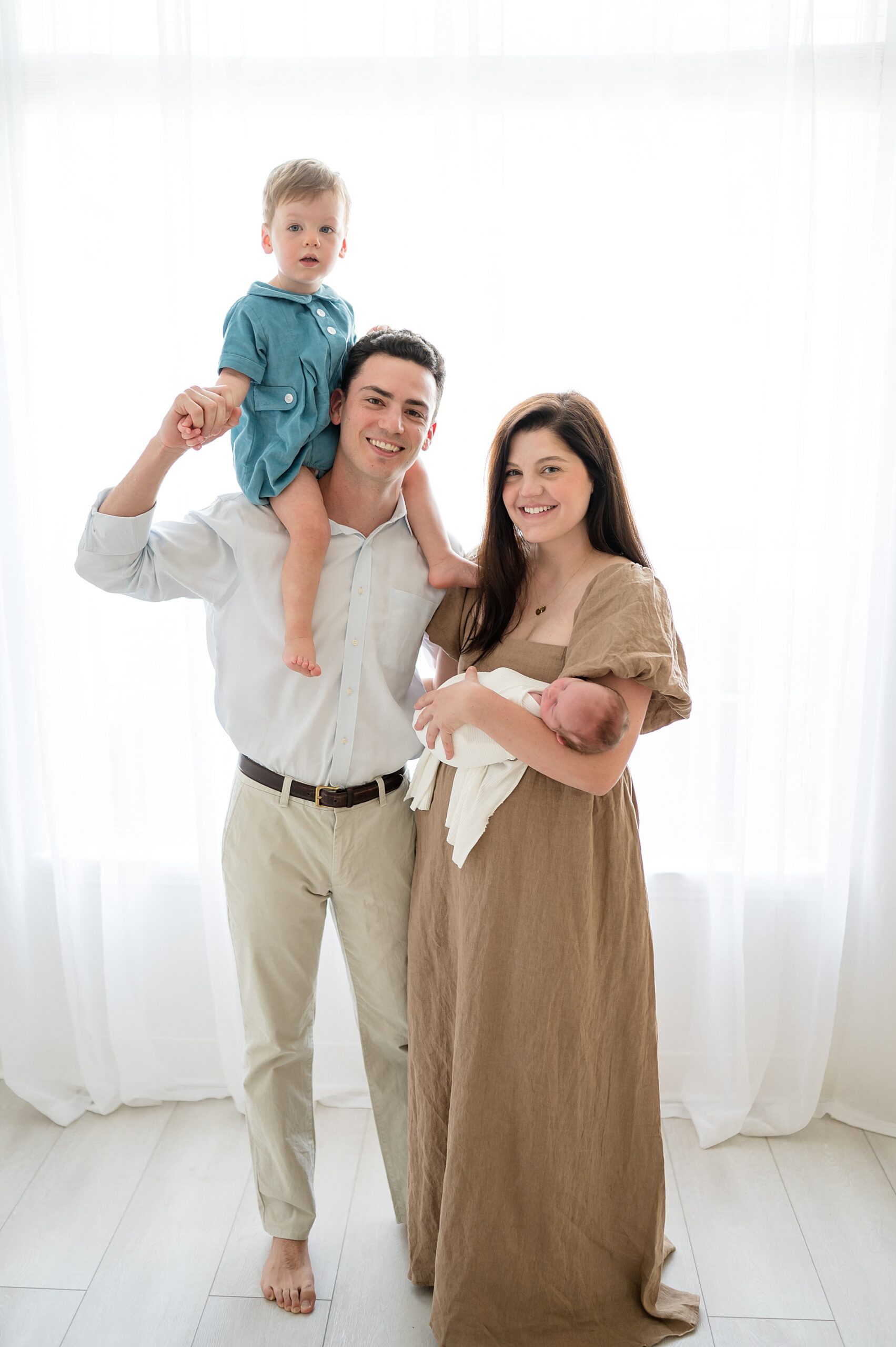 mom holds newborn and dad holds son on his shoulder | newborn photographer in Plano Texas