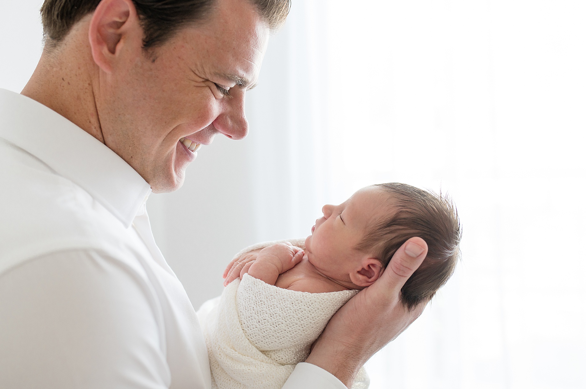 light and airy newborn photos of dad and baby by photographer in Frisco TX