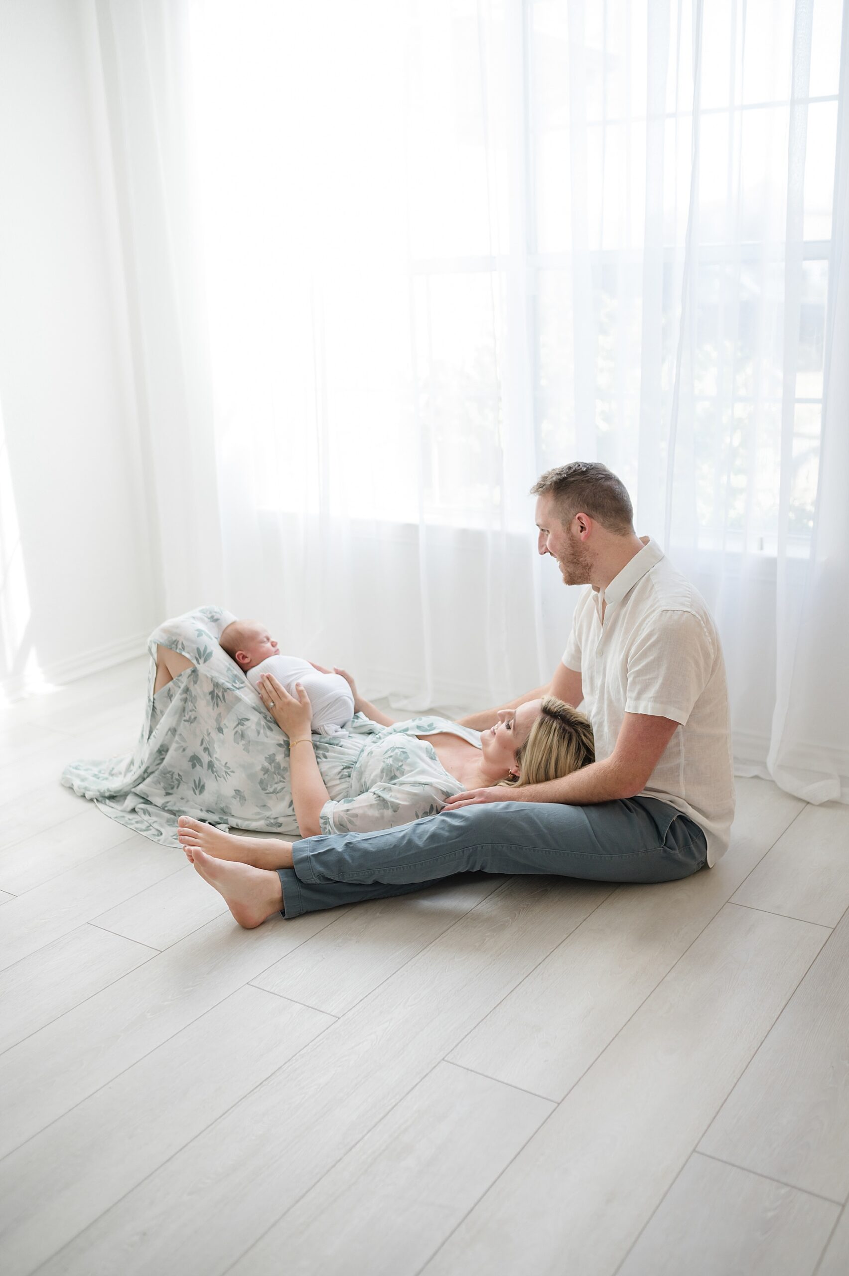 mom with newborn in lap lays on husband's lap