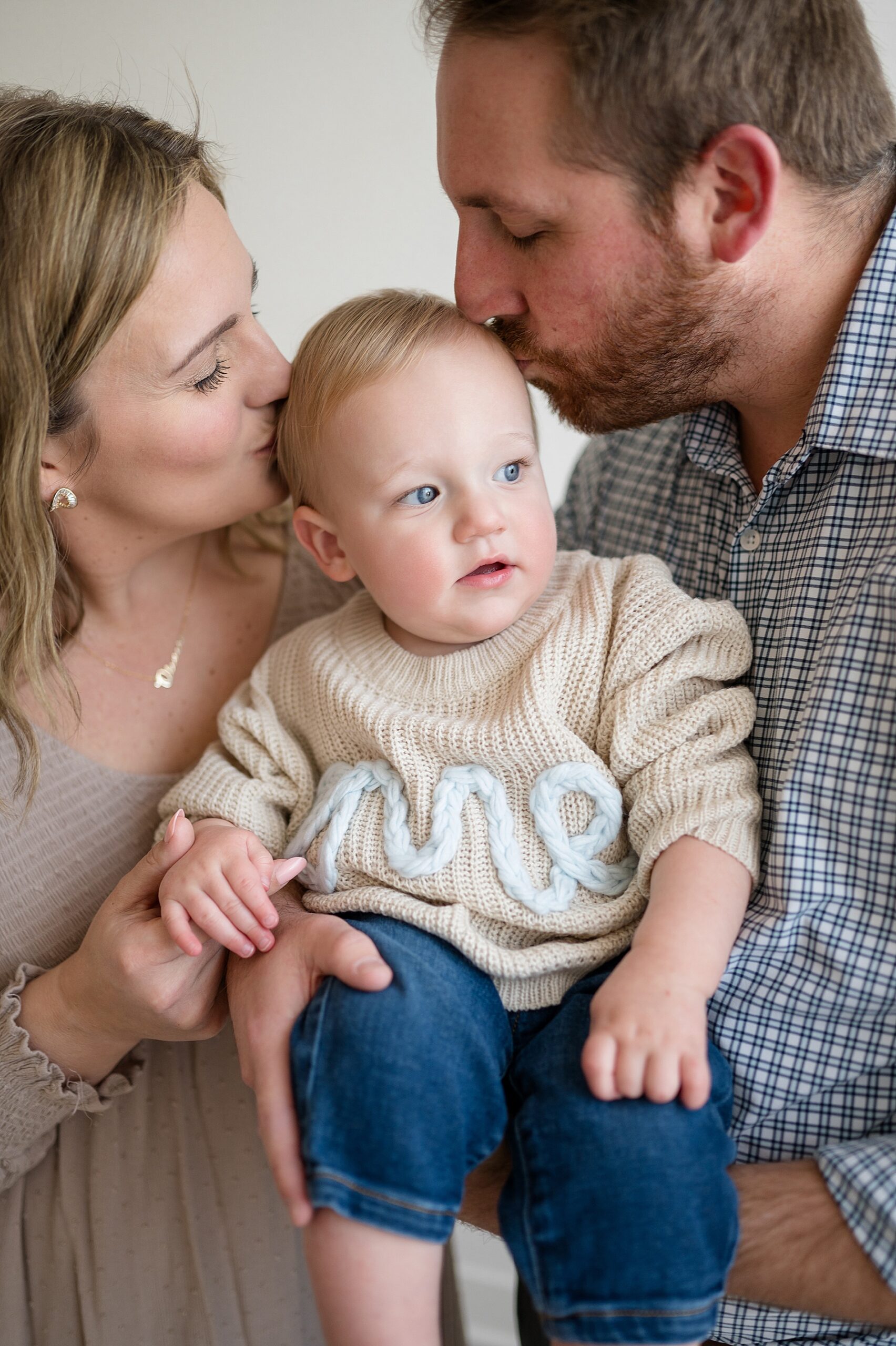parents kiss baby's head during first year photo session