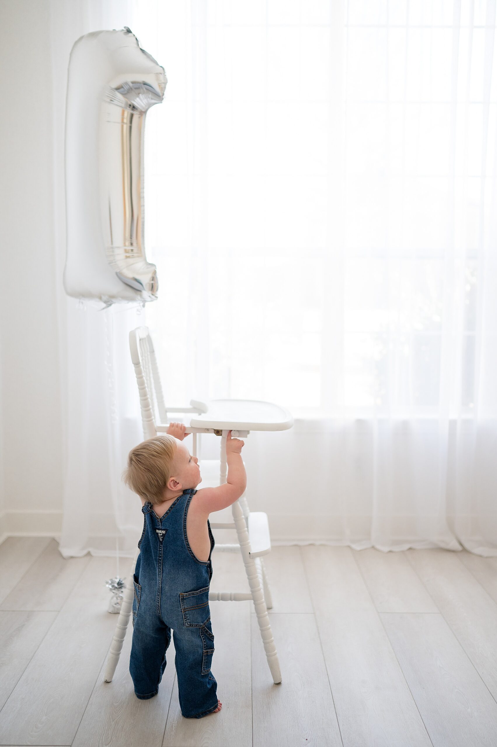 baby boy stands by high chair