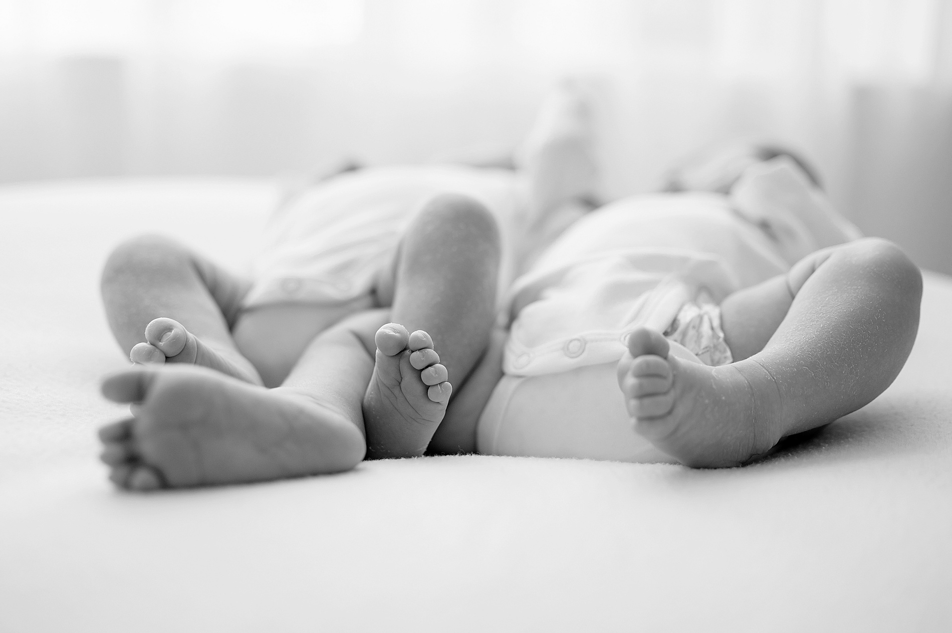 twins laying next to each other during studio session by Newborn photographer in Frisco TX